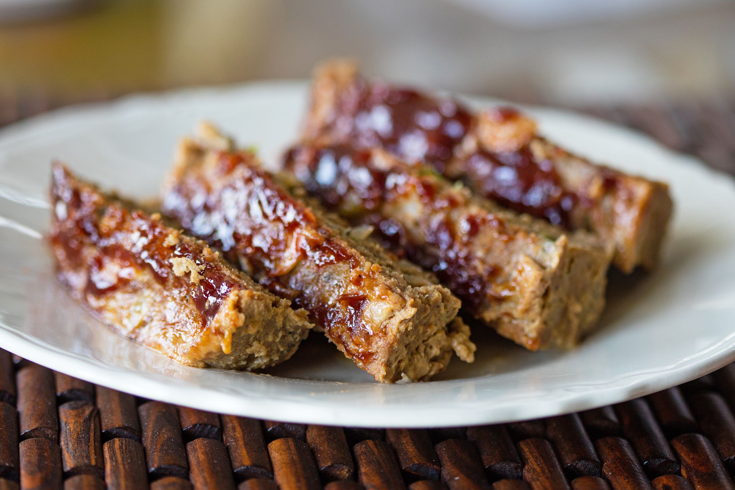 Four pieces of air fryer meatloaf on a white plate with blurred background