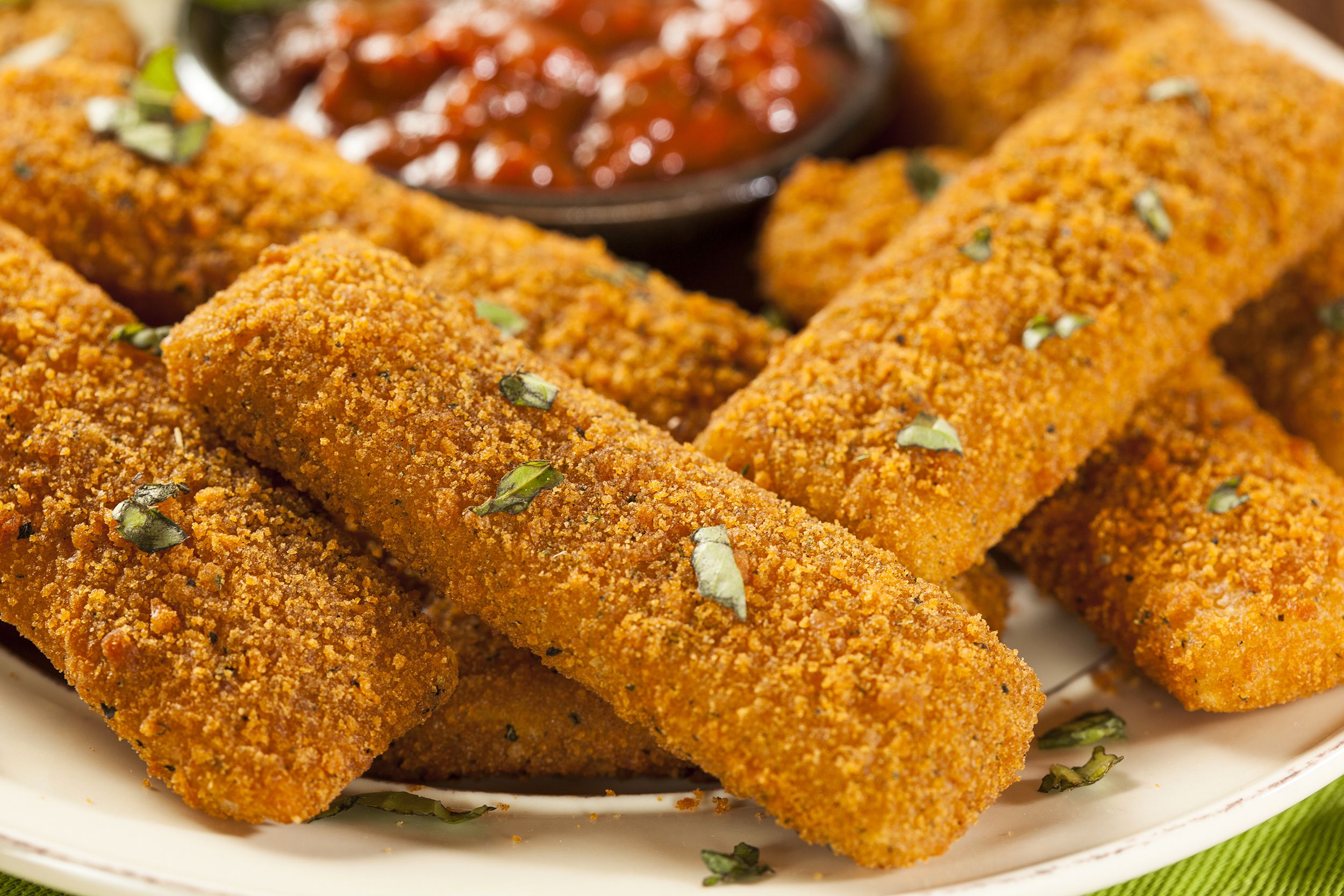 Air fryer mozzarella sticks with marinara sauce on white plate