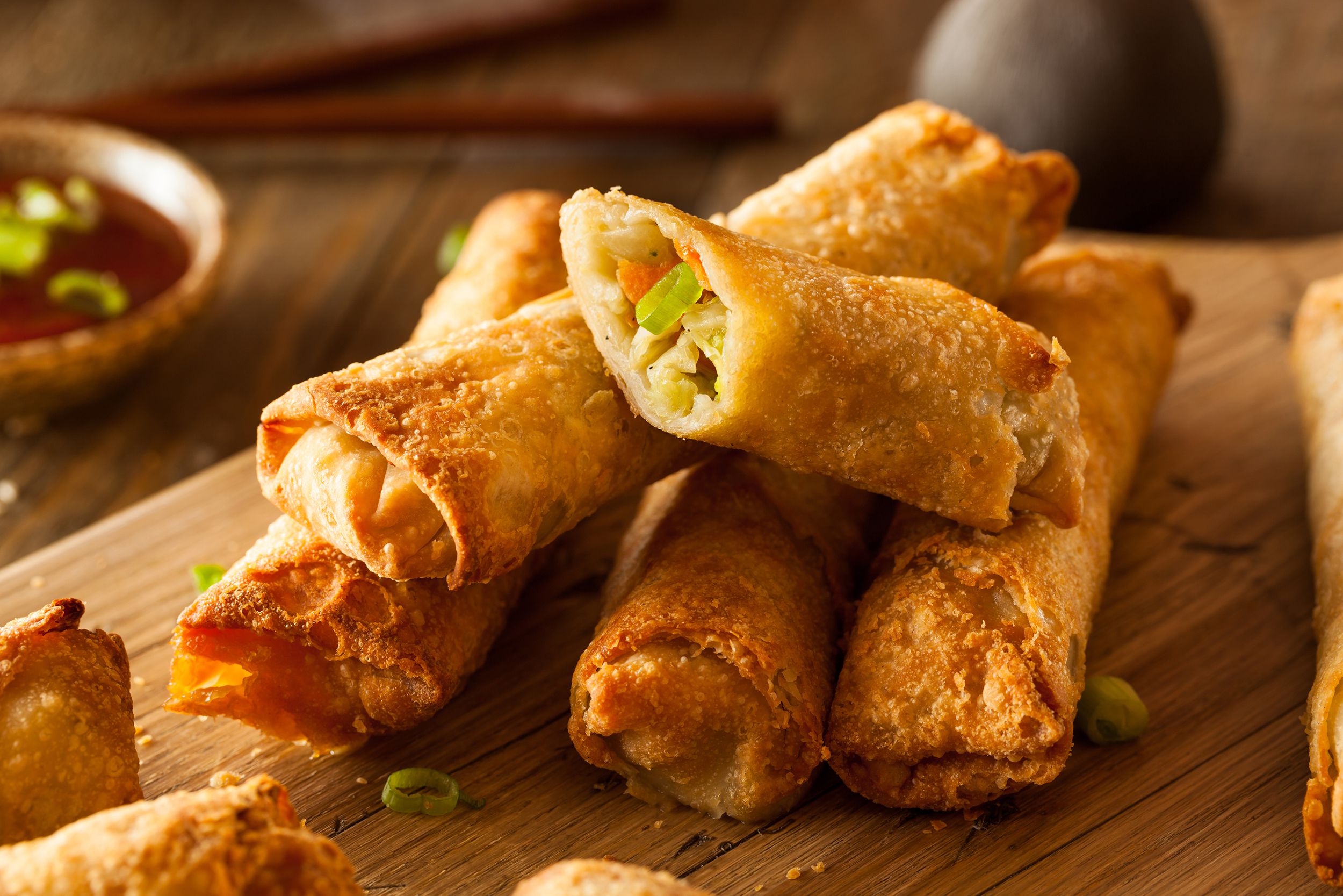 Closeup of air fryer new york style egg rolls made with shrimp and pork, on a wooden cutting board with blurred background