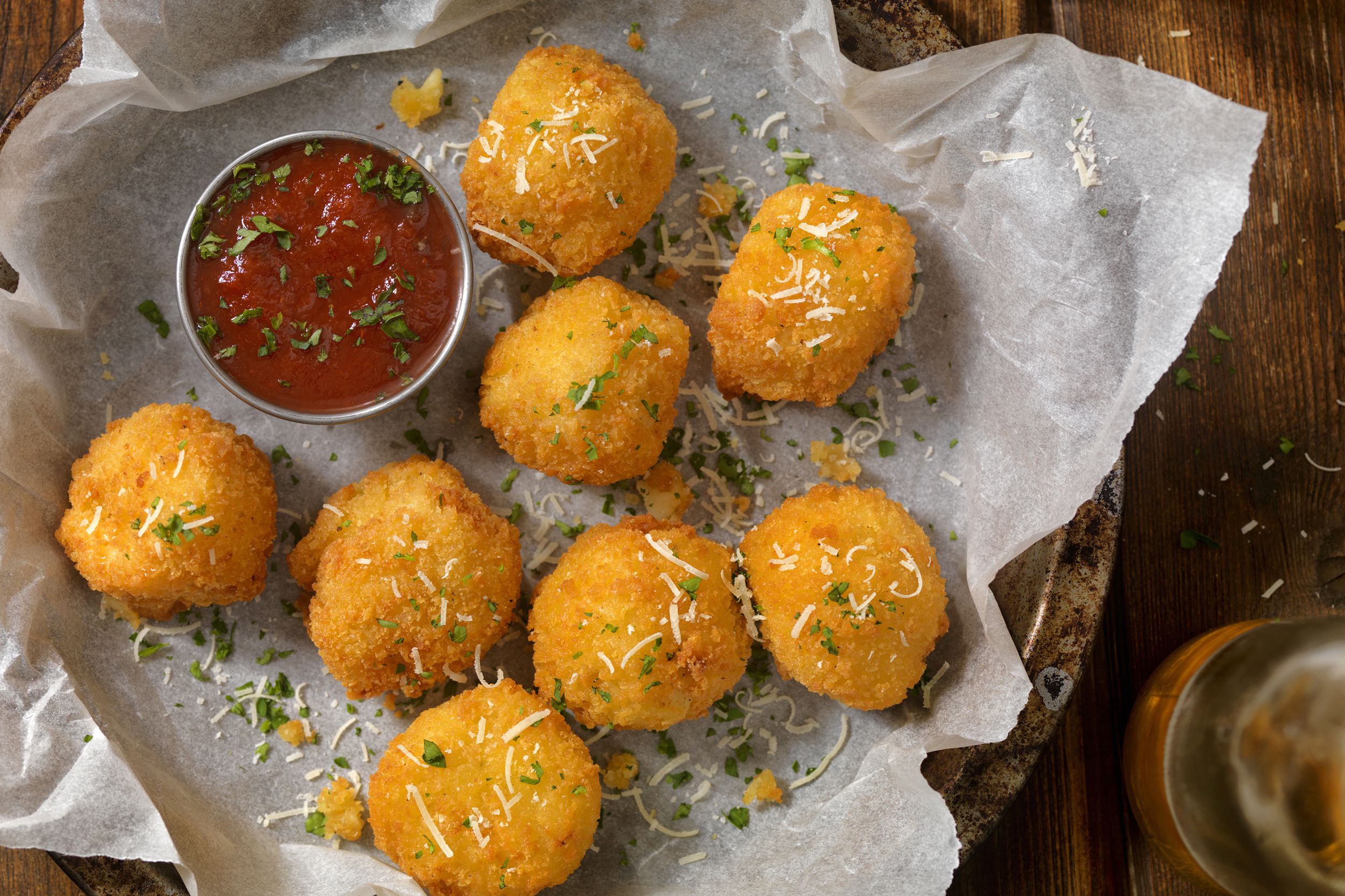 Air fryer parmesan 'fried' tortellini with marinara sauce served on paper in bowl on wooden table