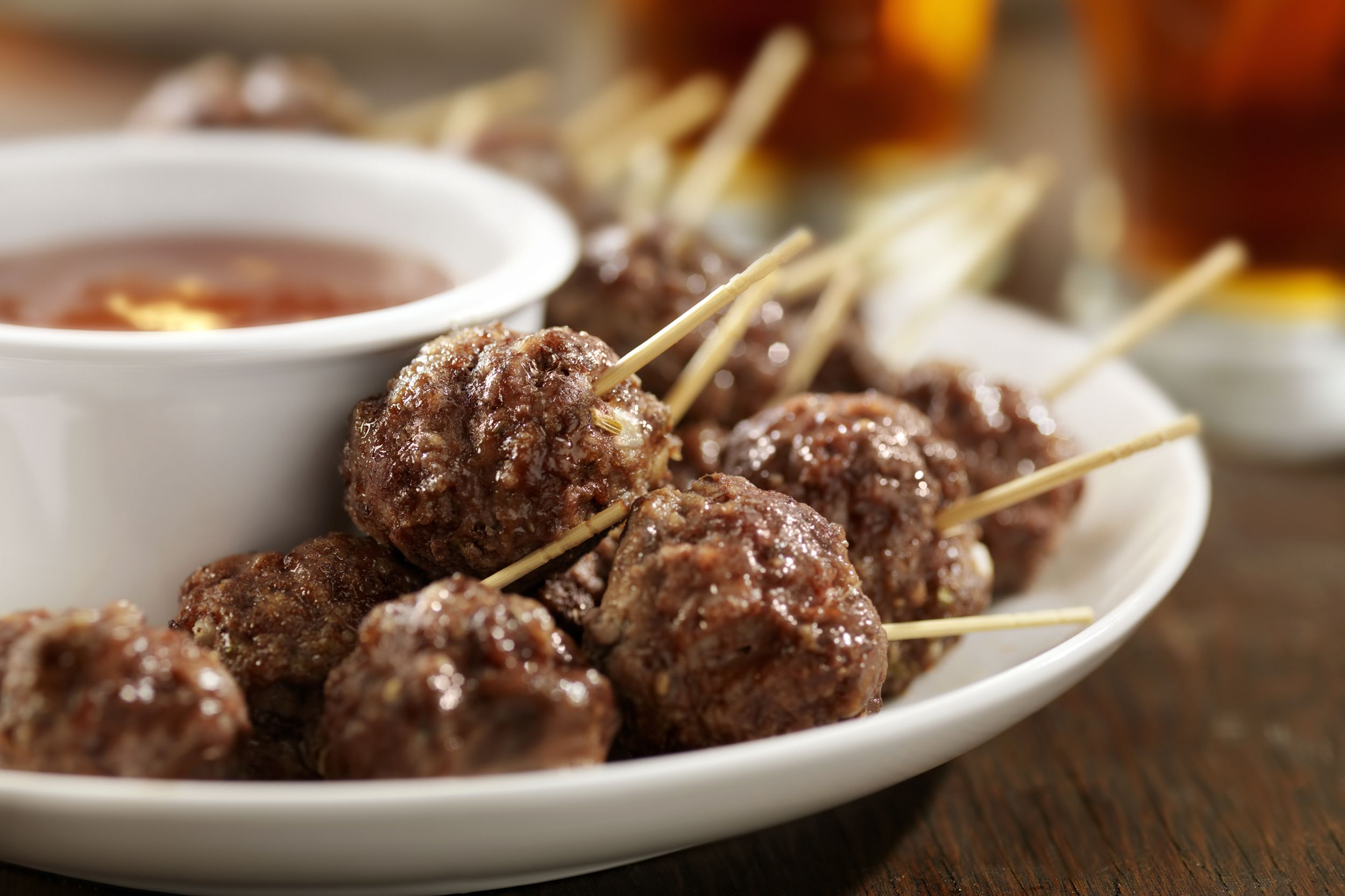 Closeup of air fryer party meatballs each one with a toothpick for guests, with marinara sauce, blurred background