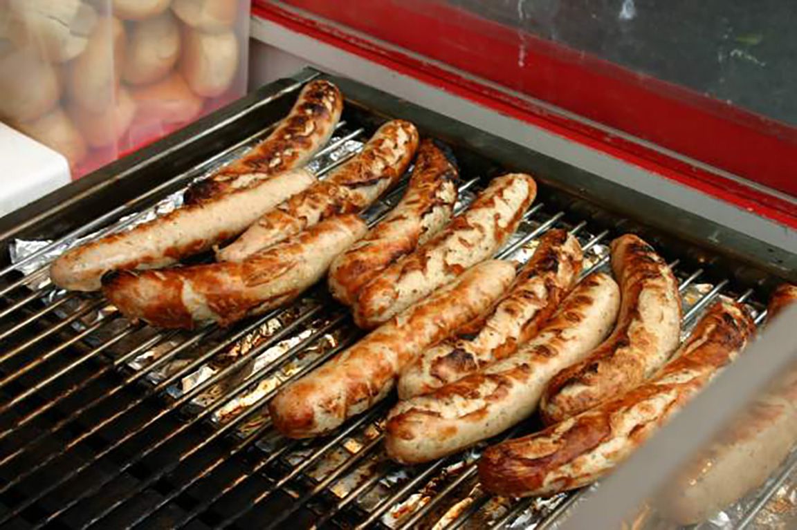 A bunch of bratwurst on a grill.