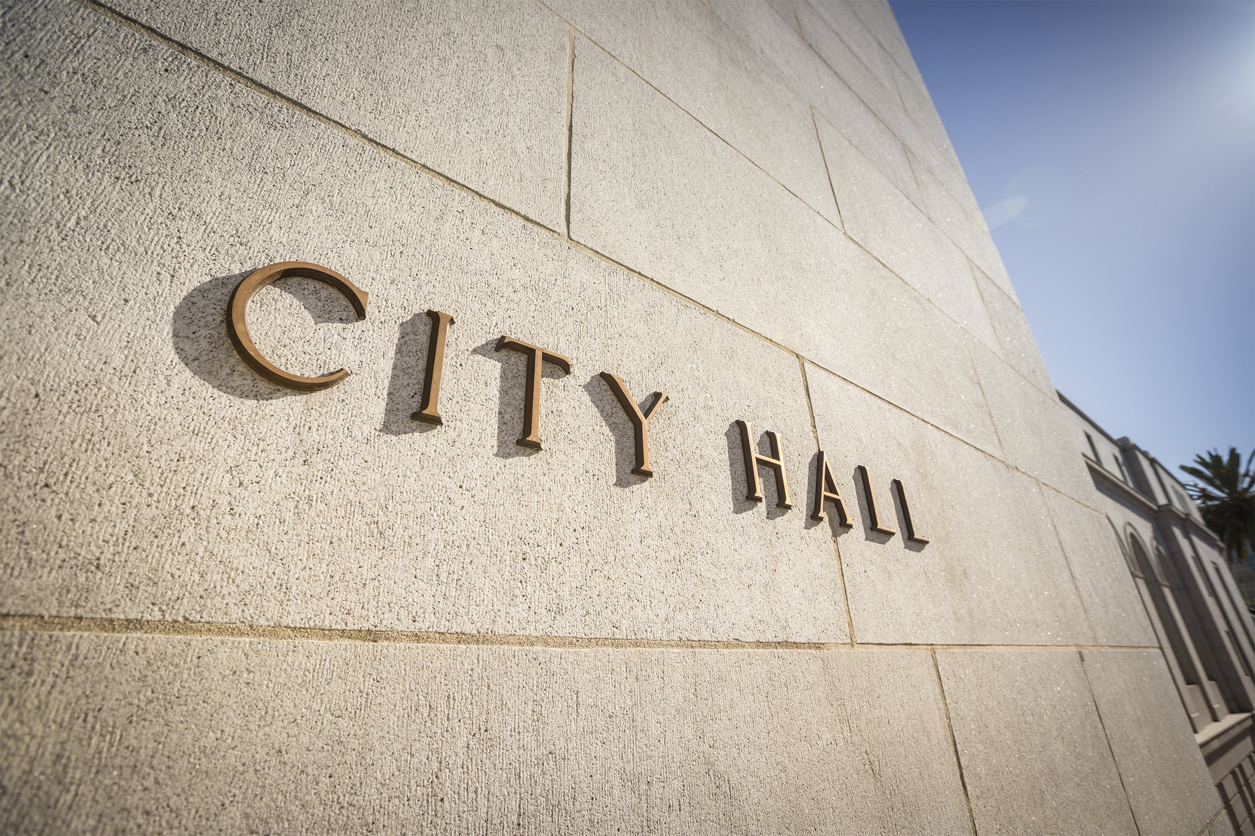 Closeup of the brass sign of city hall on entrance doorway into building in Los Angeles with blue sky in the top right corner
