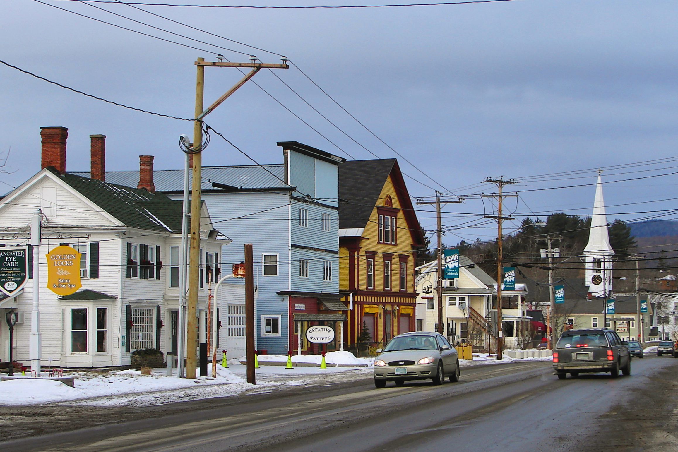 Dirty snow with old cars driving on a street in Colebrook, NH