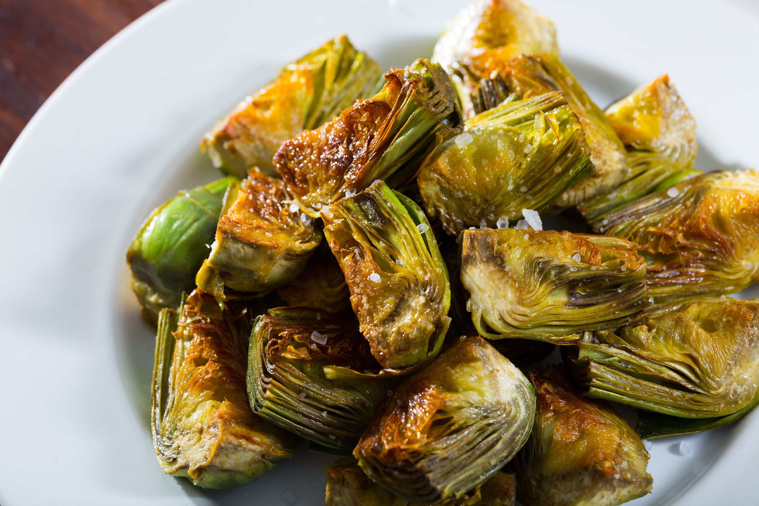 Crispy air fryer artichoke hearts with horseradish sauce on a white plate