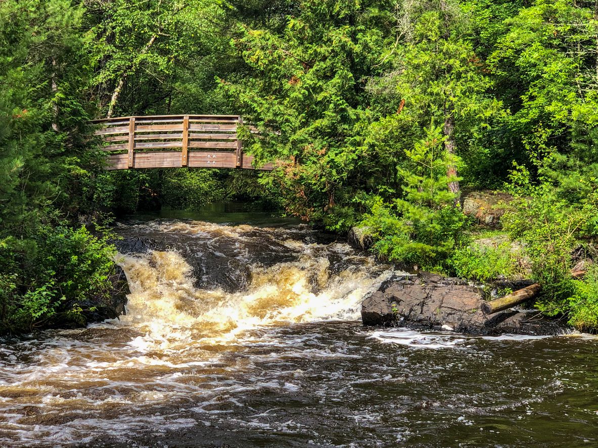 View of wooden arched bridge over a waterfall in Crivitz, Wisconsin