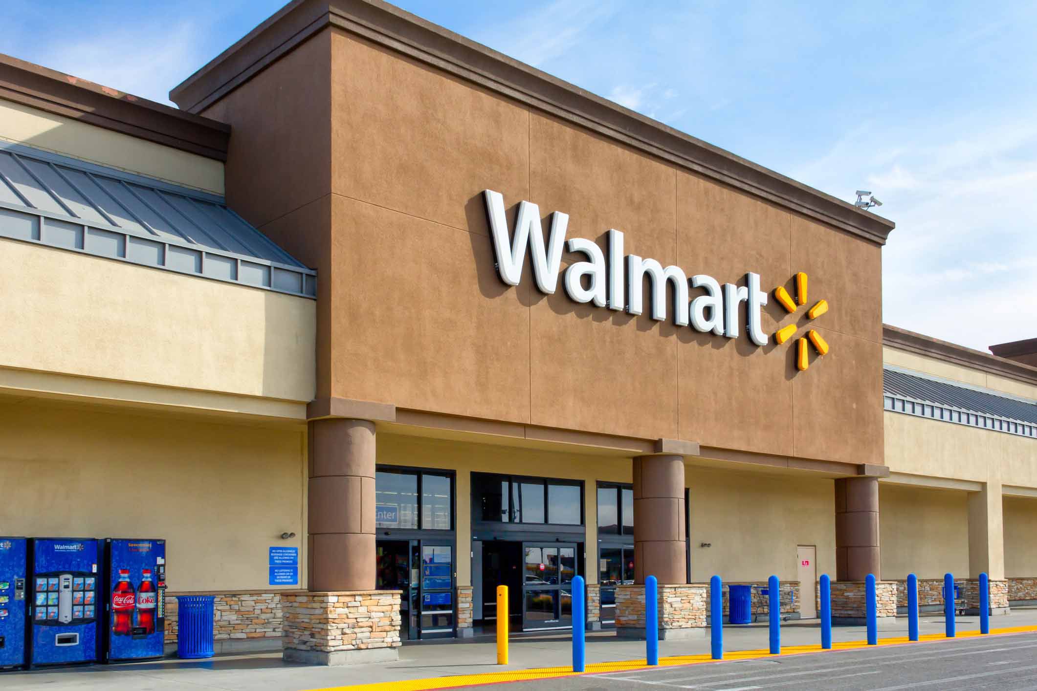 Exterior of Walmart store front doors opened, vending machines to the right, very clean, on a sunny day