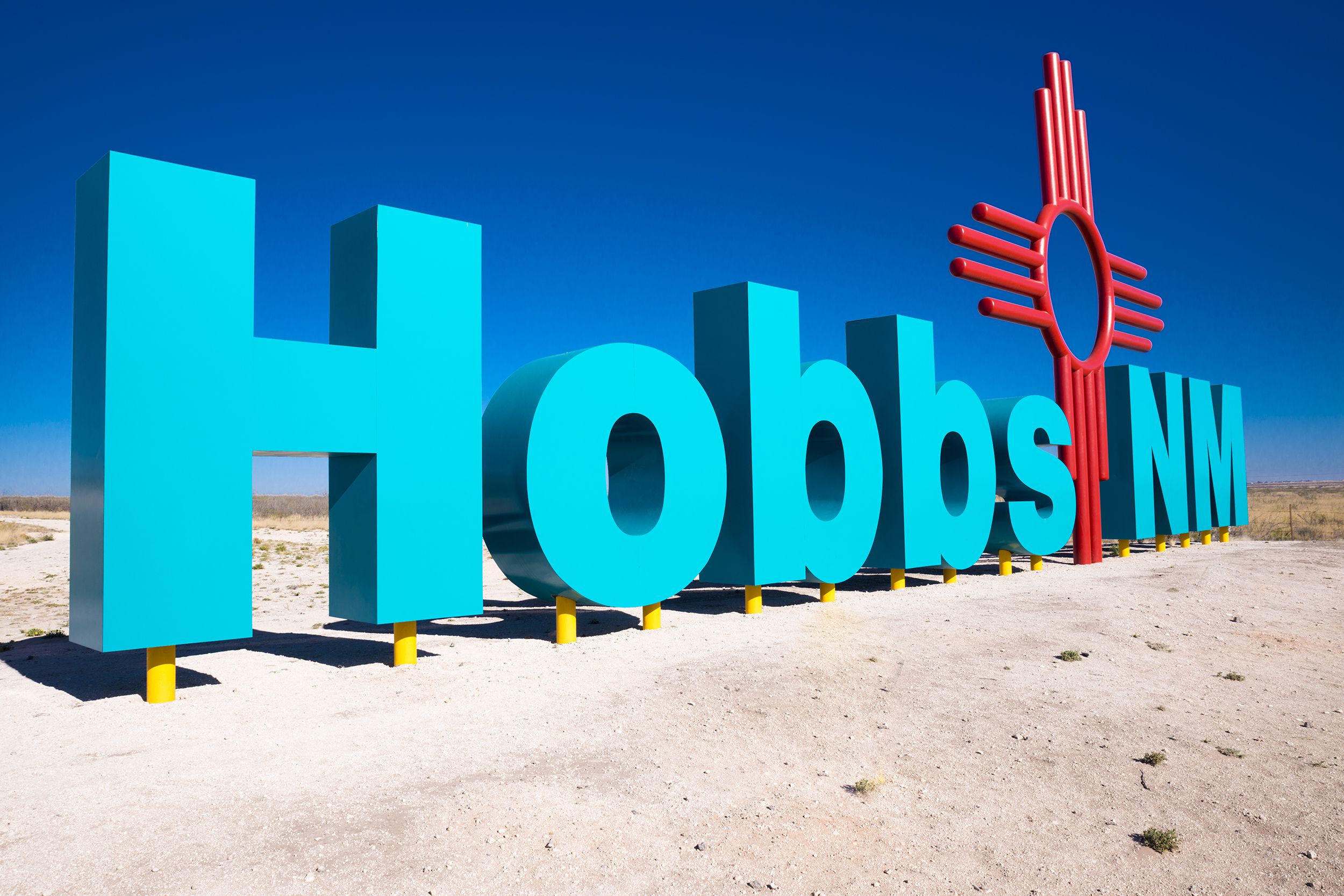 Giant blue vertical letters spelling out Hobbs, NM on beach