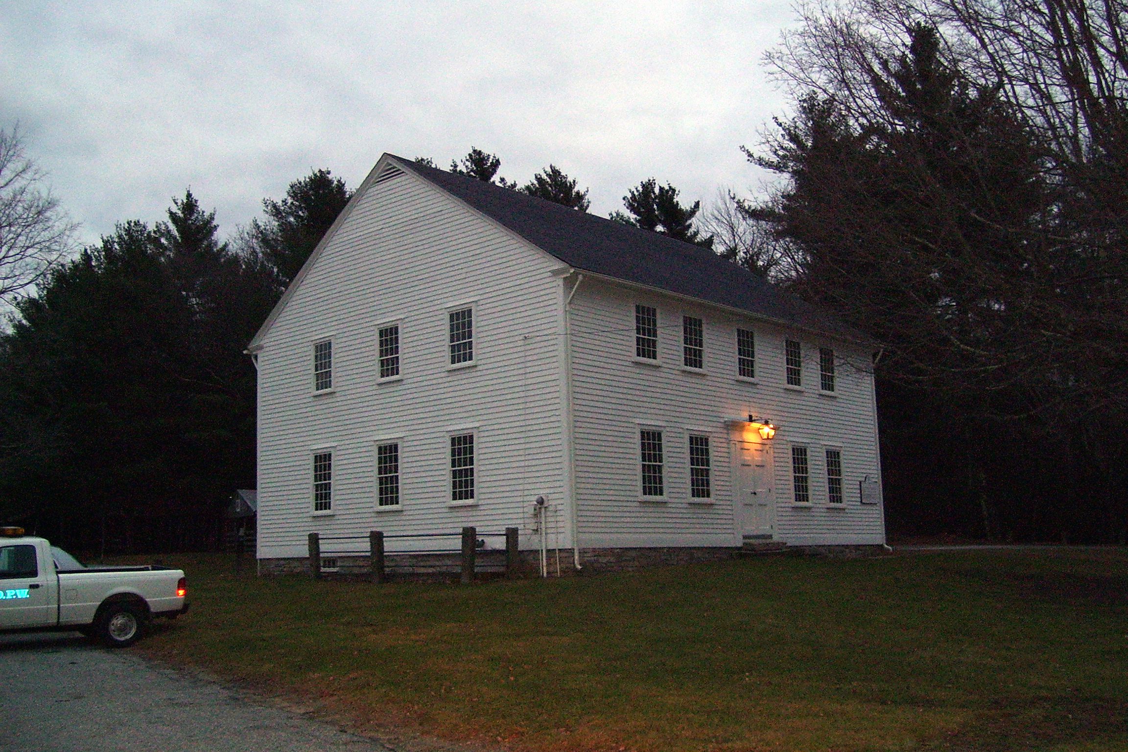Large white house at dusk with lit porch light in North Foster, Rhode Island