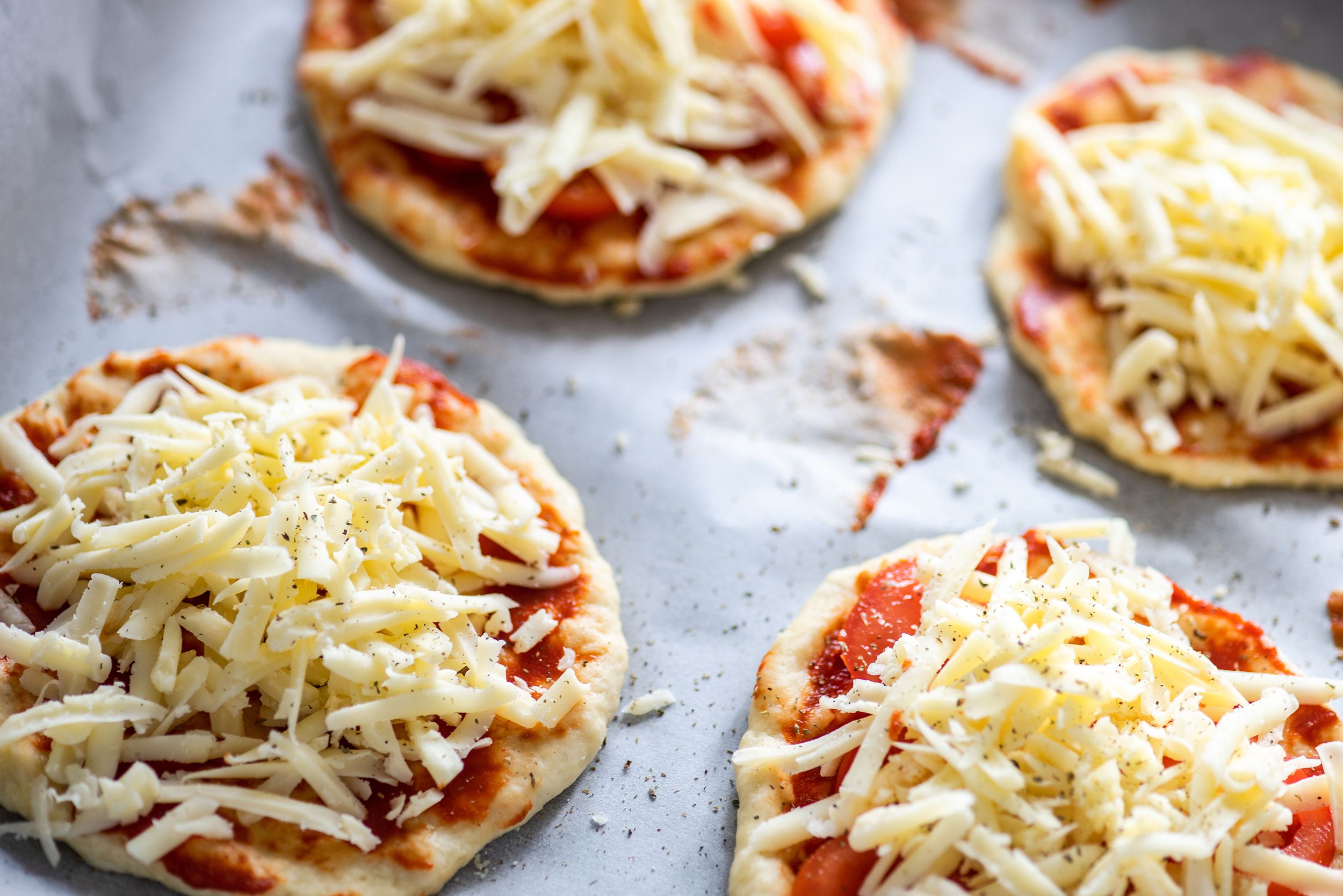 Perfect personal pizzas in an air fryer with cheese topping on a baking sheet