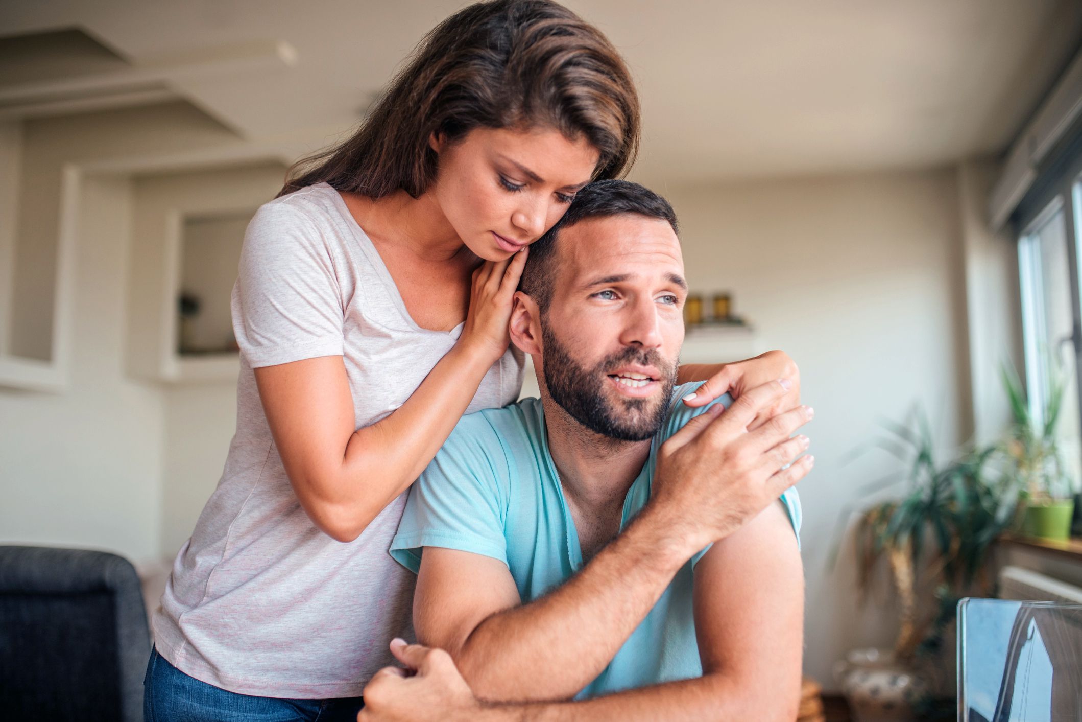 young woman comforting nervous-looking man with arm around him