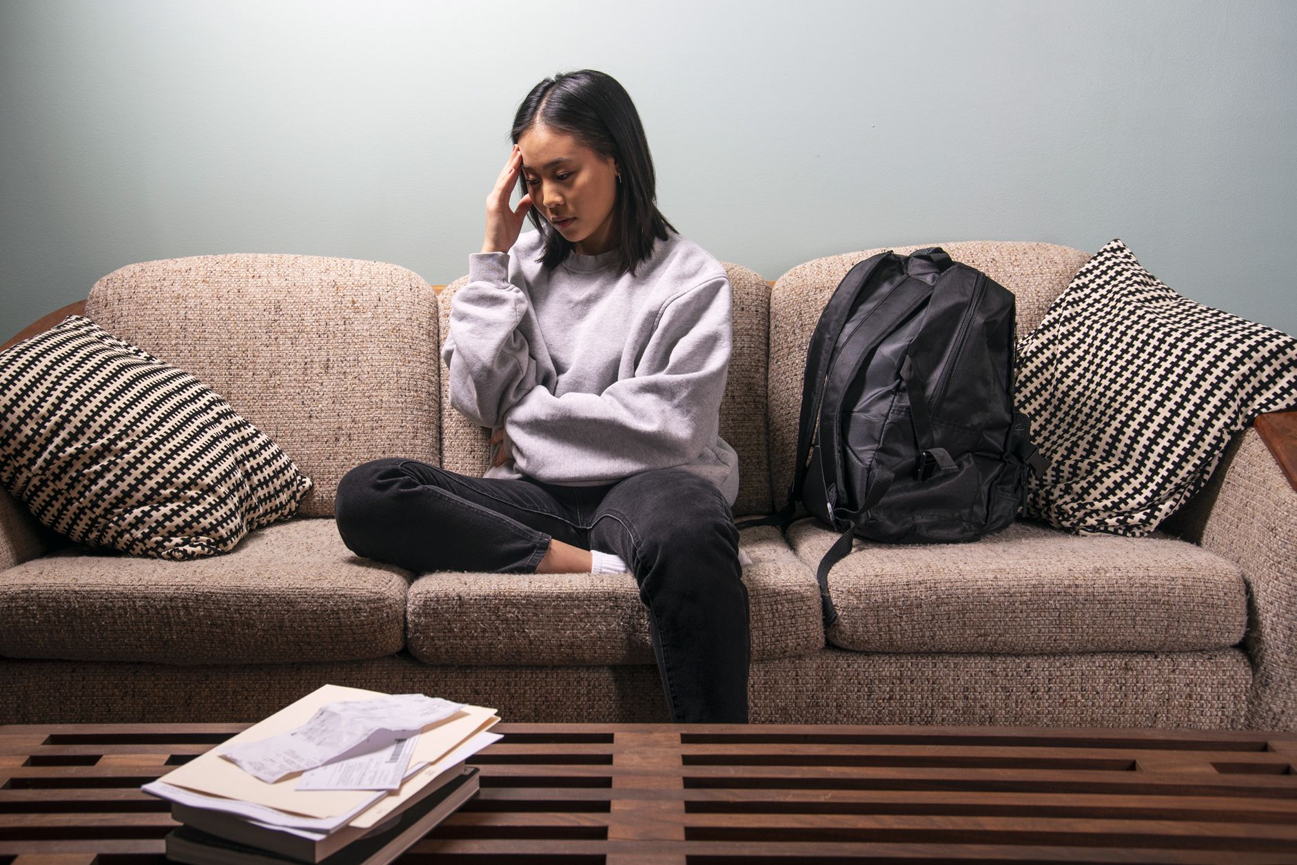 woman sitting on couch looking uncomfortable and sad