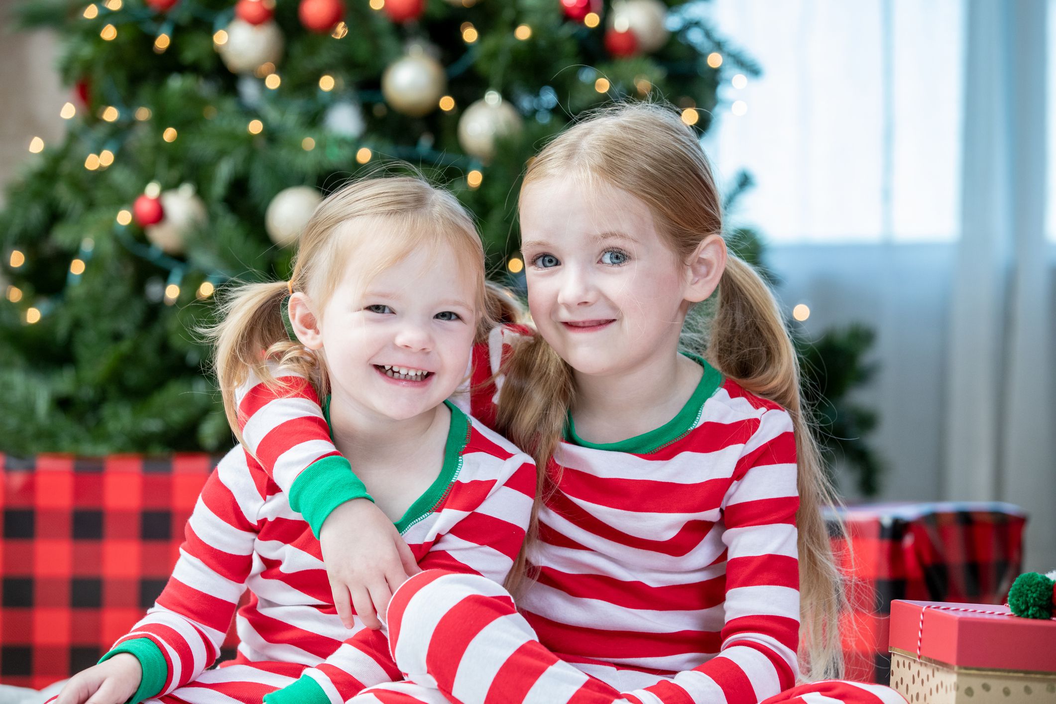 Sisters smiling in front of Christmas tree