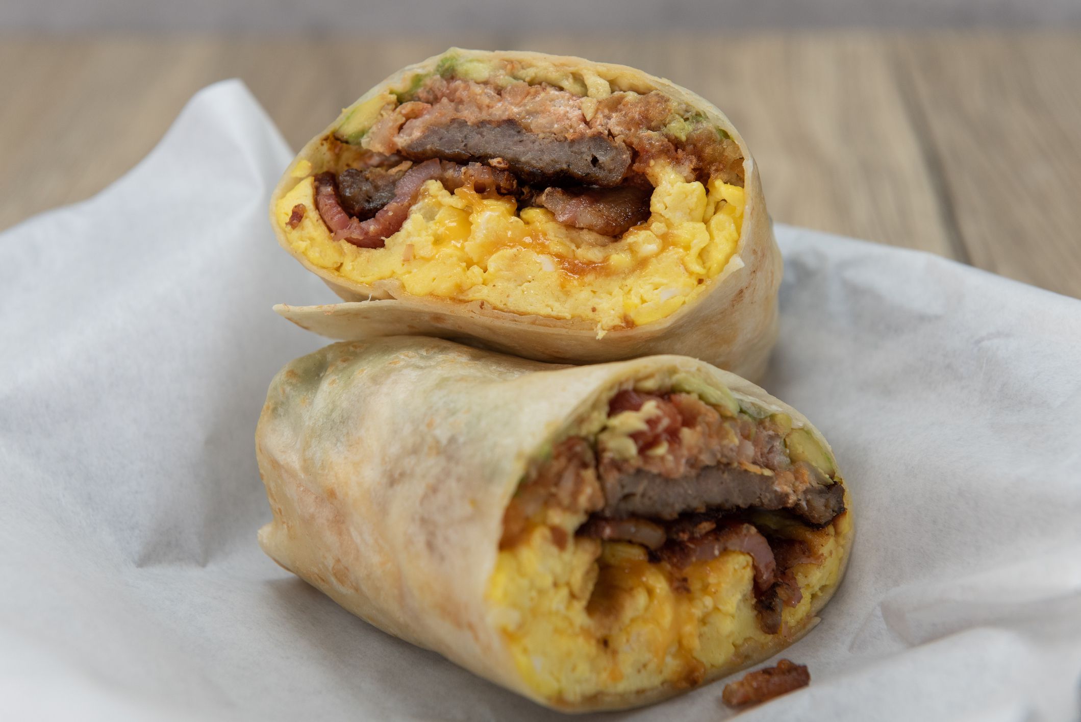 Tasty and hearty steak and eggs breakfast burrito cut in half to show the bursting ingredients.