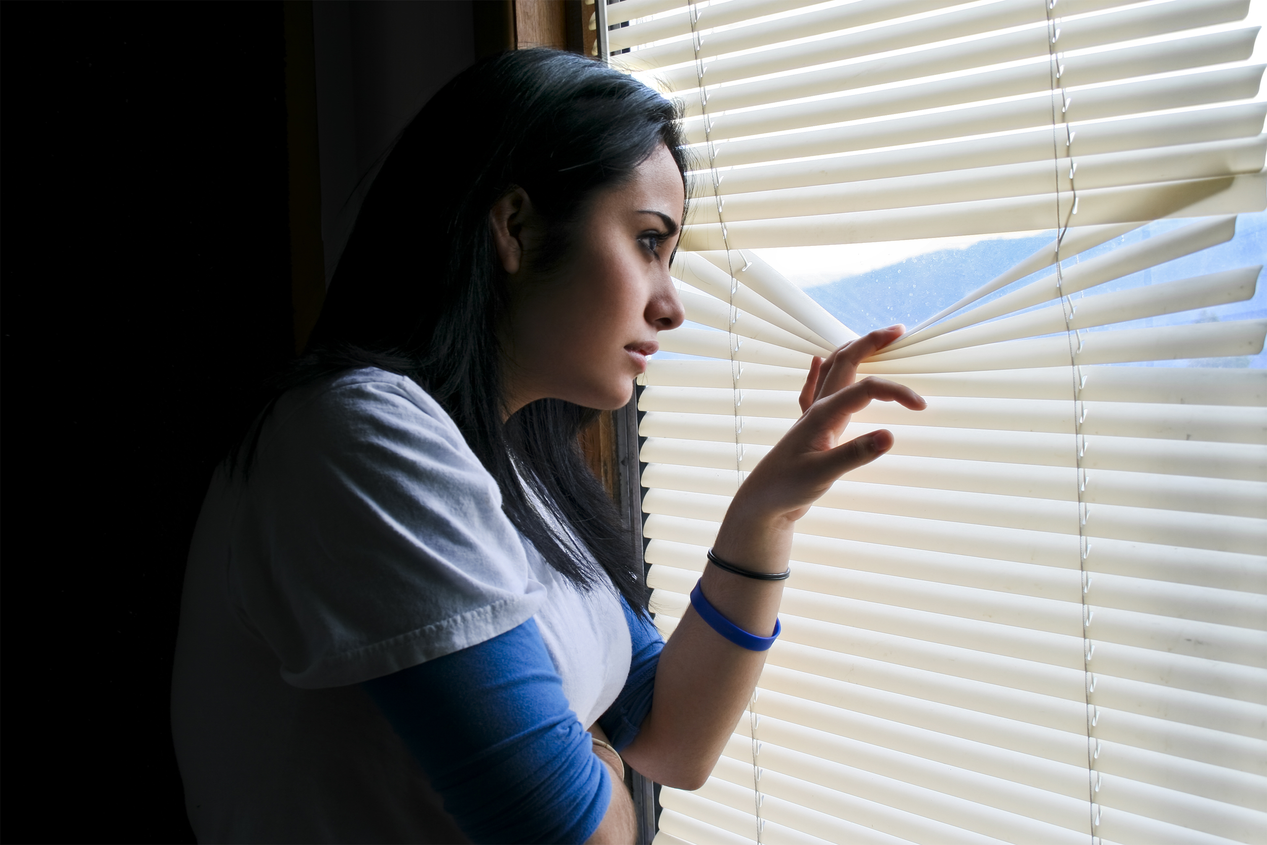 paranoid woman looking through blinds