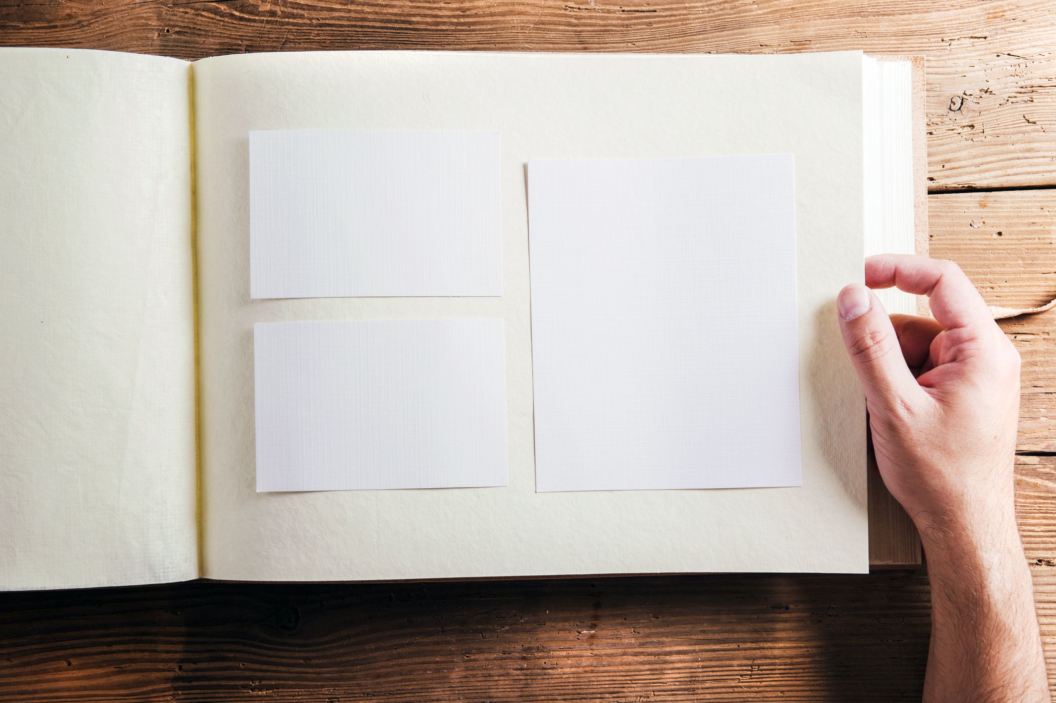 open photo album with blank white spaces instead of photos, hand turning page