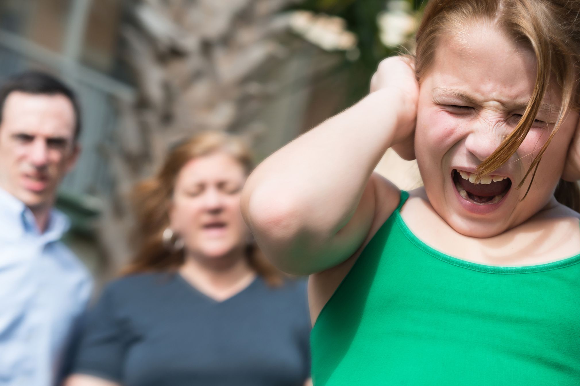 screaming child, parents looking concerned in background