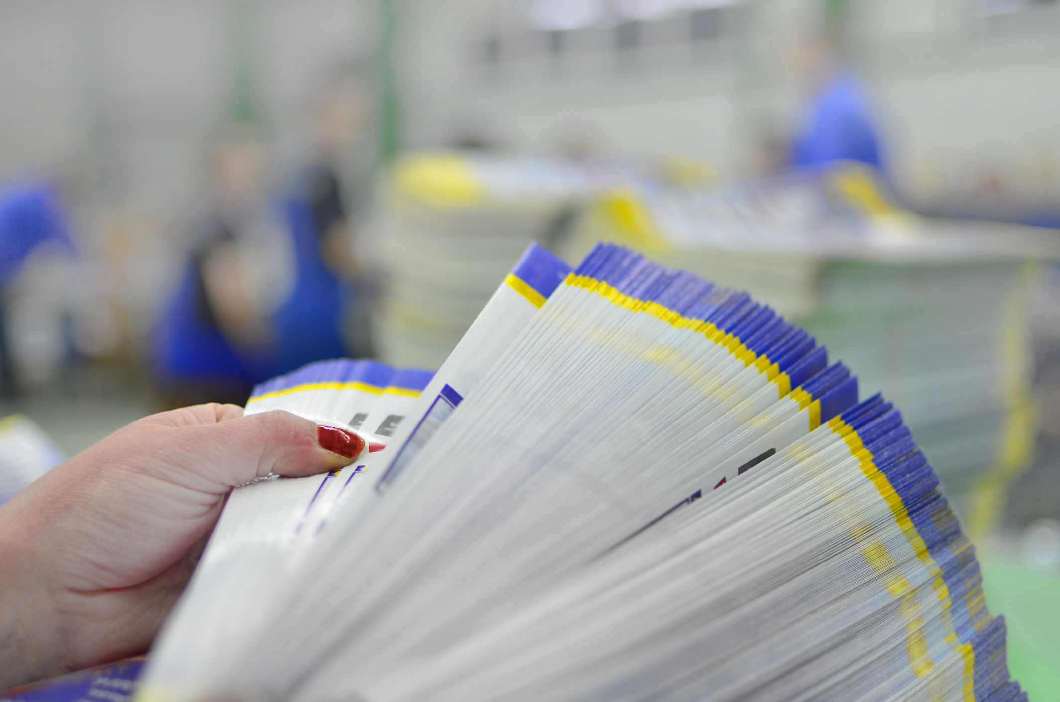 Manual controll and count of printed material packets with blur workers at background