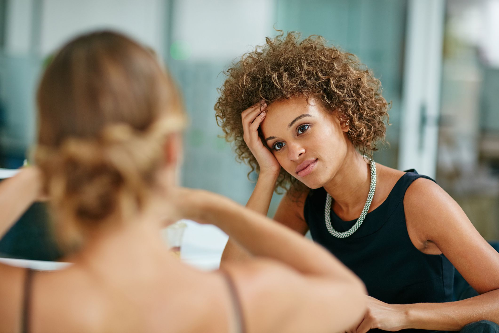woman looking somewhat sad, hand in head, at office