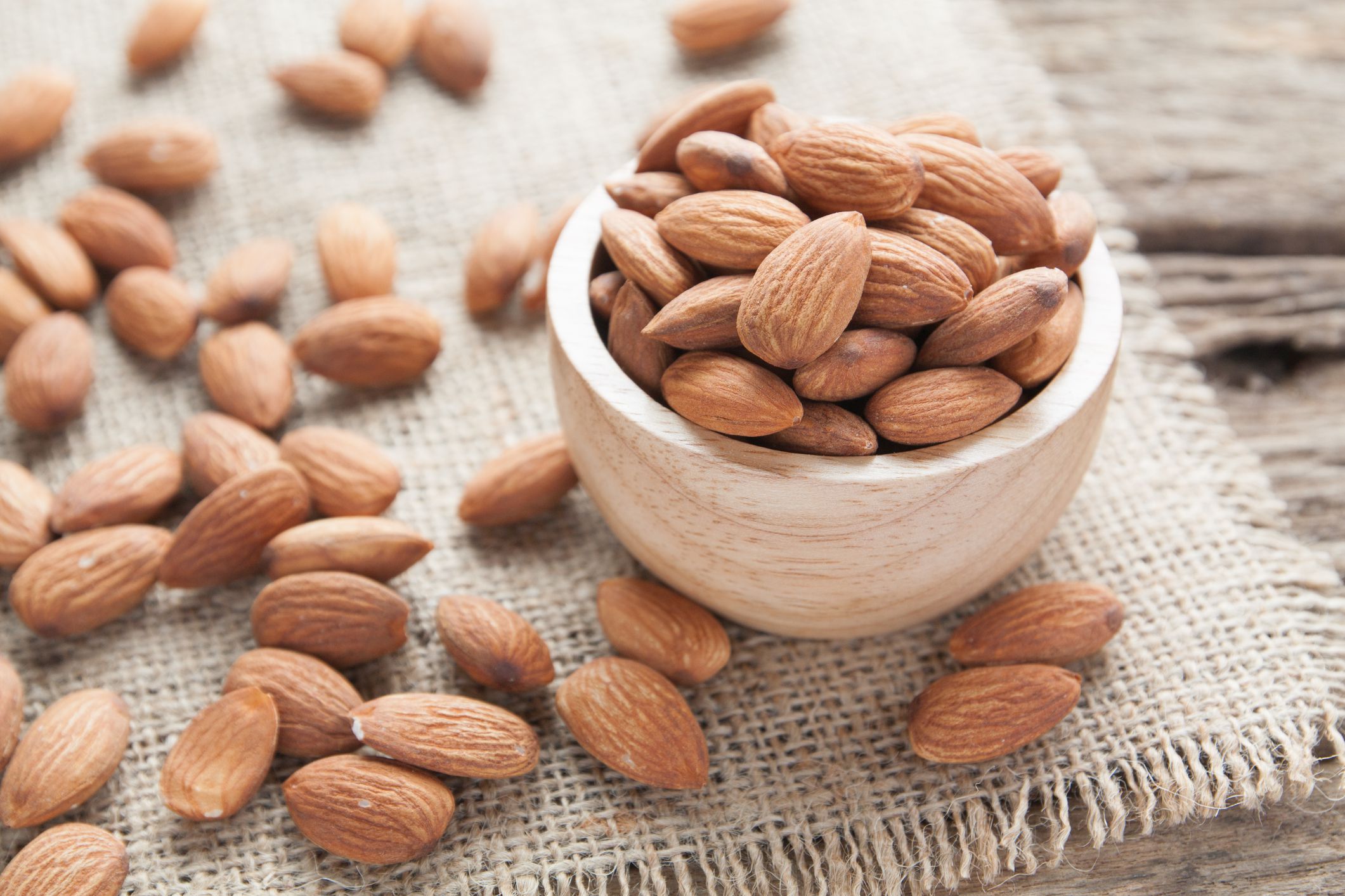 group of almonds from wood bowl on wood background