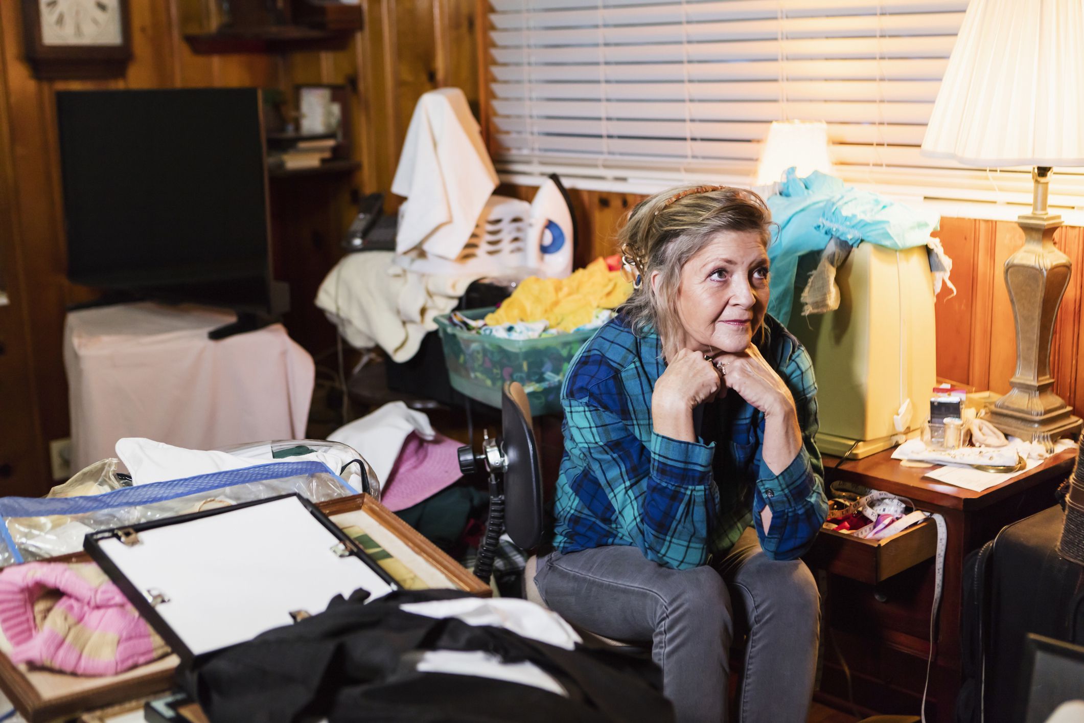 senior woman sitting in messy room overcrowded with random objects