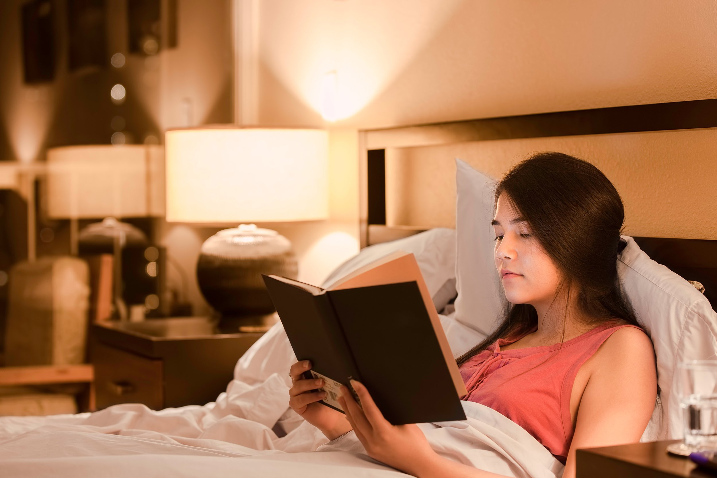 women reading book in bed before bedtime