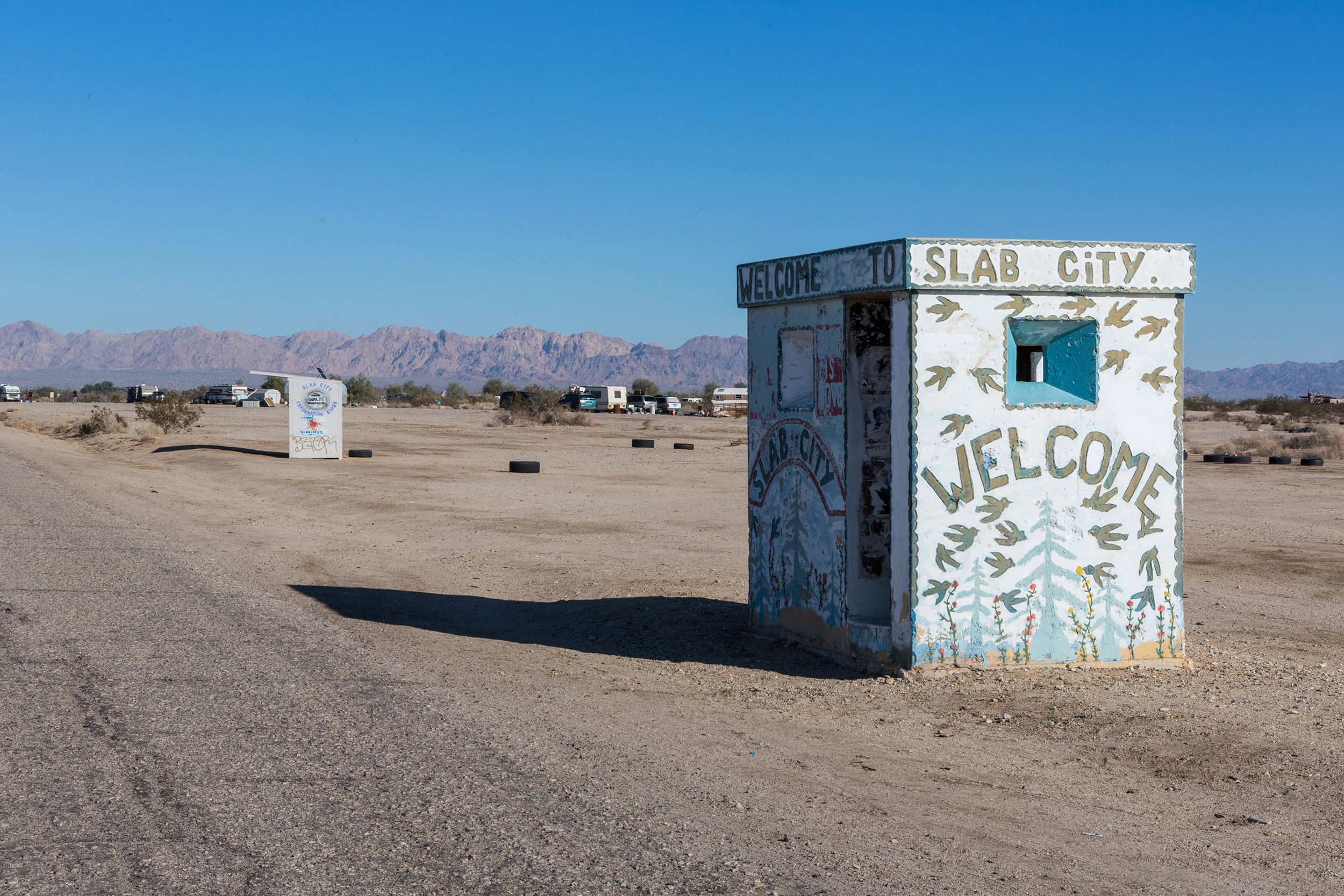 The entrance shack to Slab City located in the Sonoran Desert, California with RVs and artwork in the background
