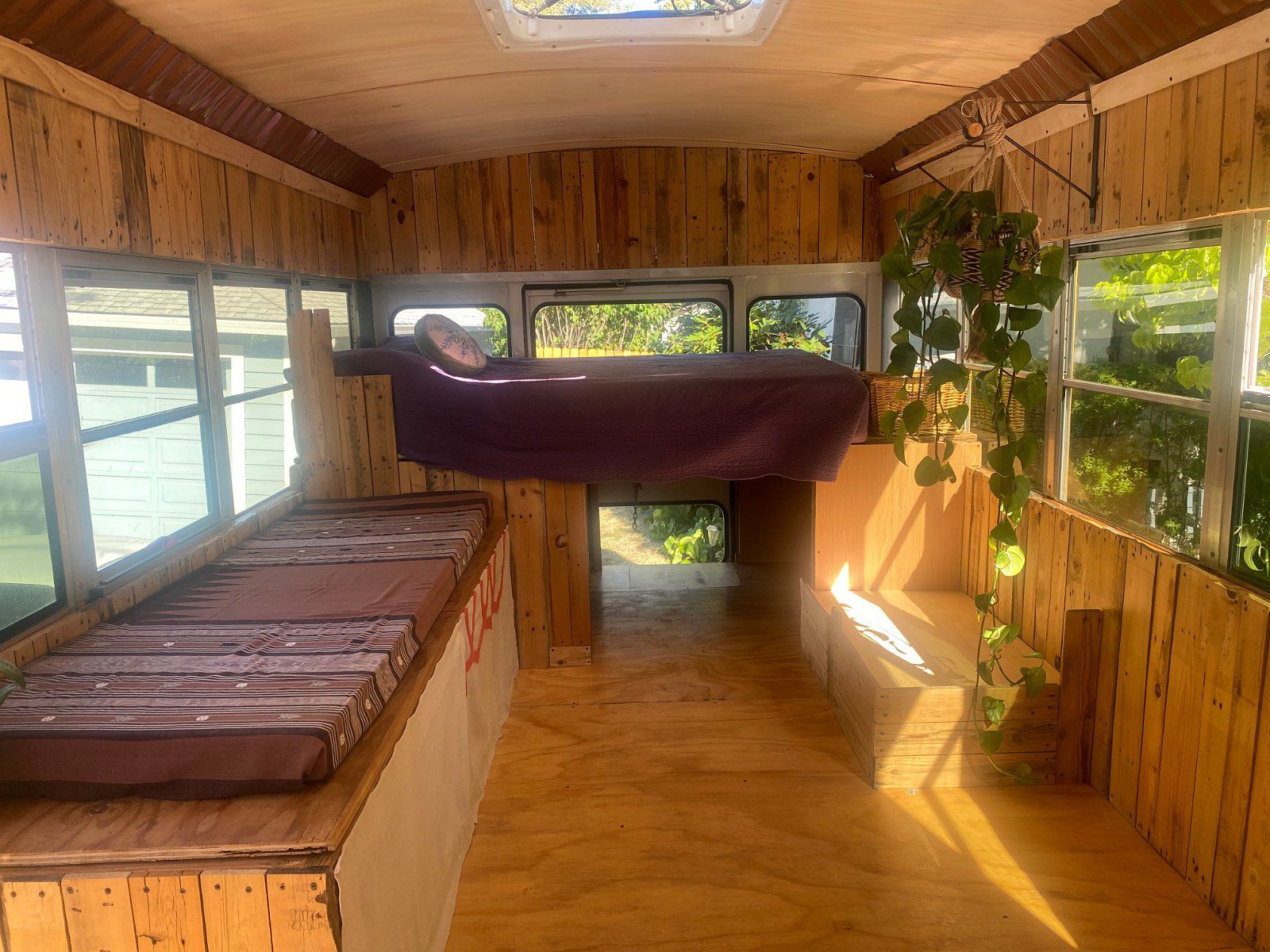 Wooden interior of Ford Collins Converted School Bus, Ashland, Oregon, loft bed and bench, on a sunny day