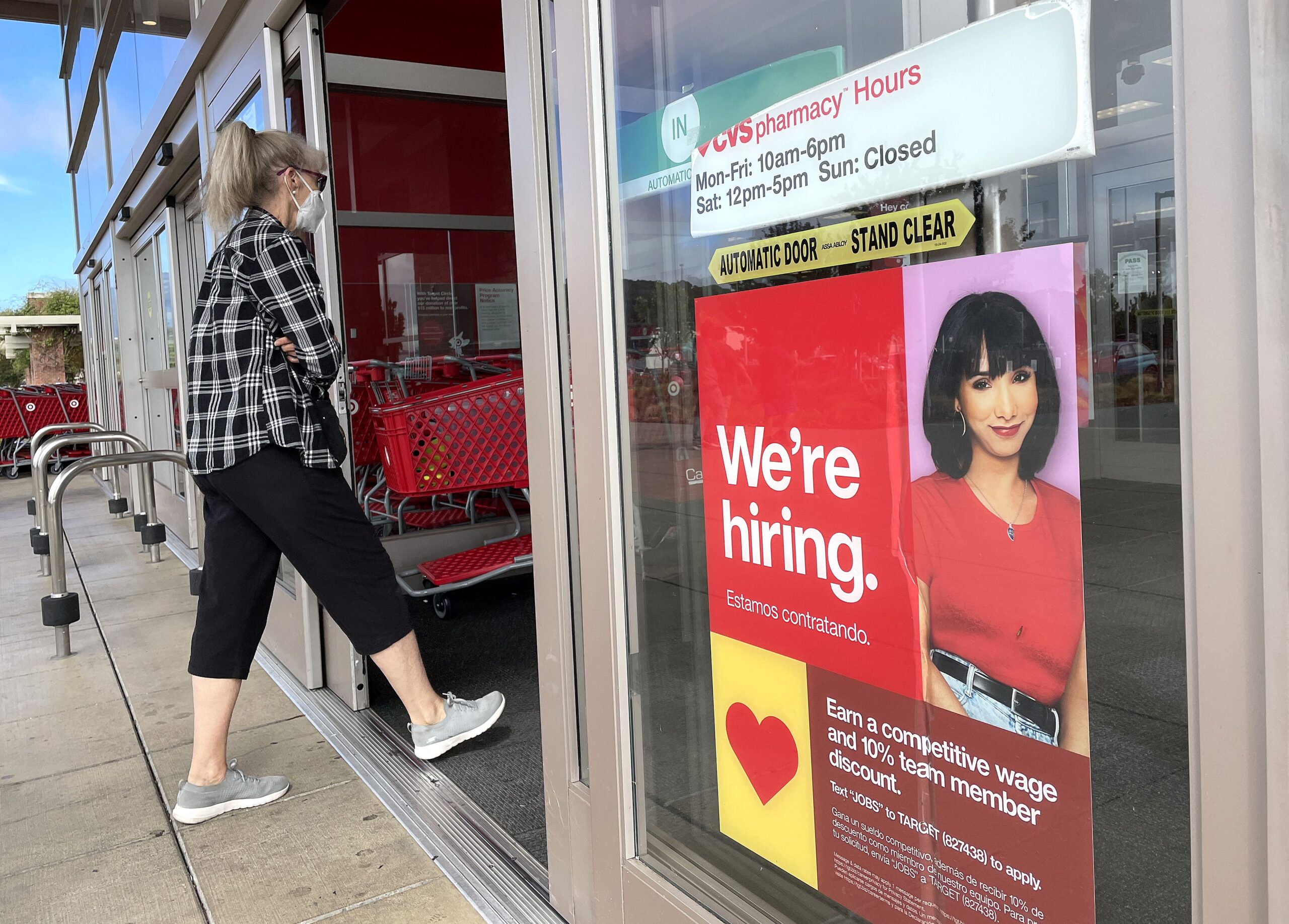 Shopper walking into Target with a hiring sign posted on the door