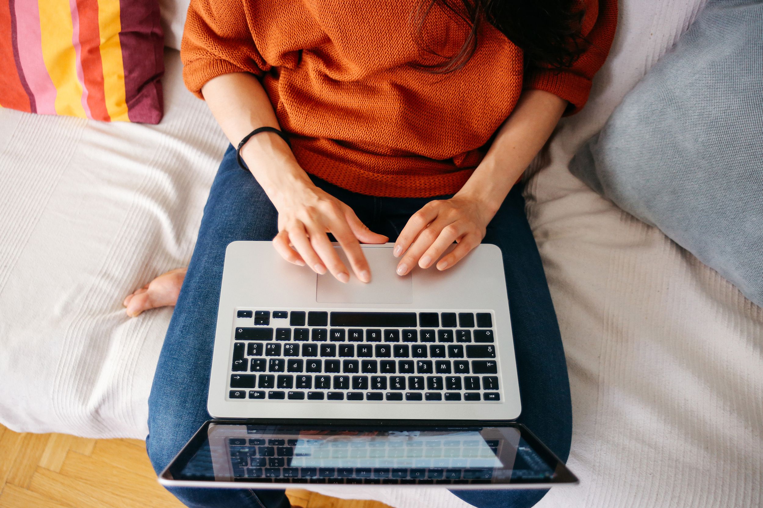Overhead view of woman sitting on bed with her laptop