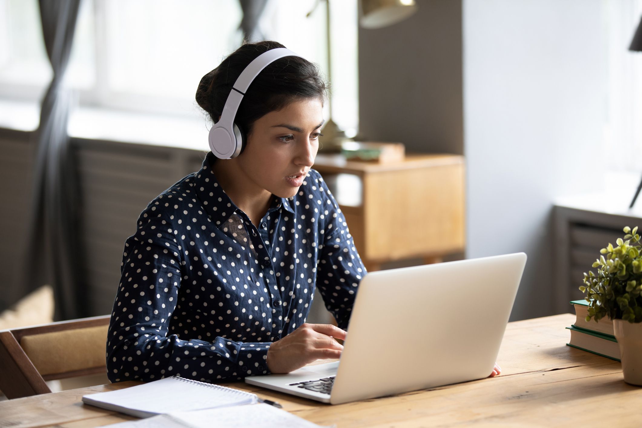 focused young woman wearing headphones looking at laptop