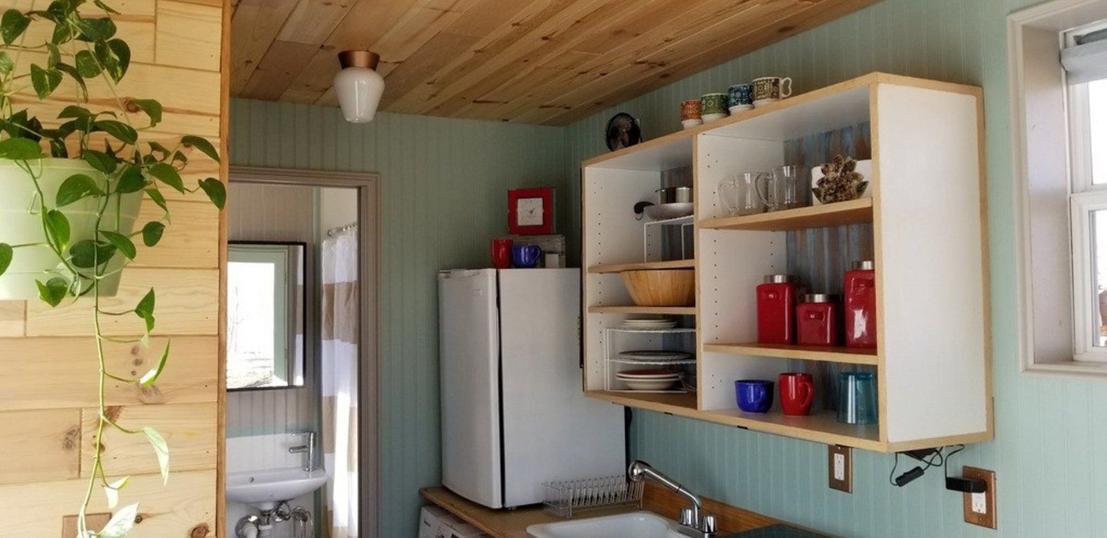 Kitchen and bathroom in Movable Container Home, Austin, Texas, clean with living Items, plant on the wall in the left foreground