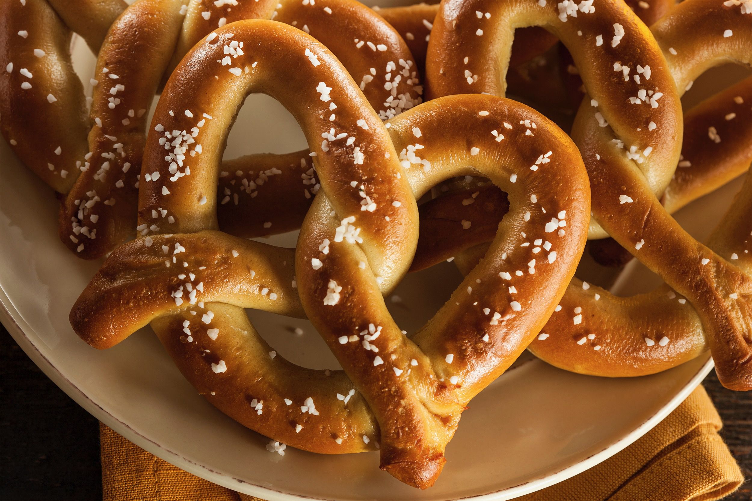 Soft Pretzels on a white plate on top of a yellow cloth napkin