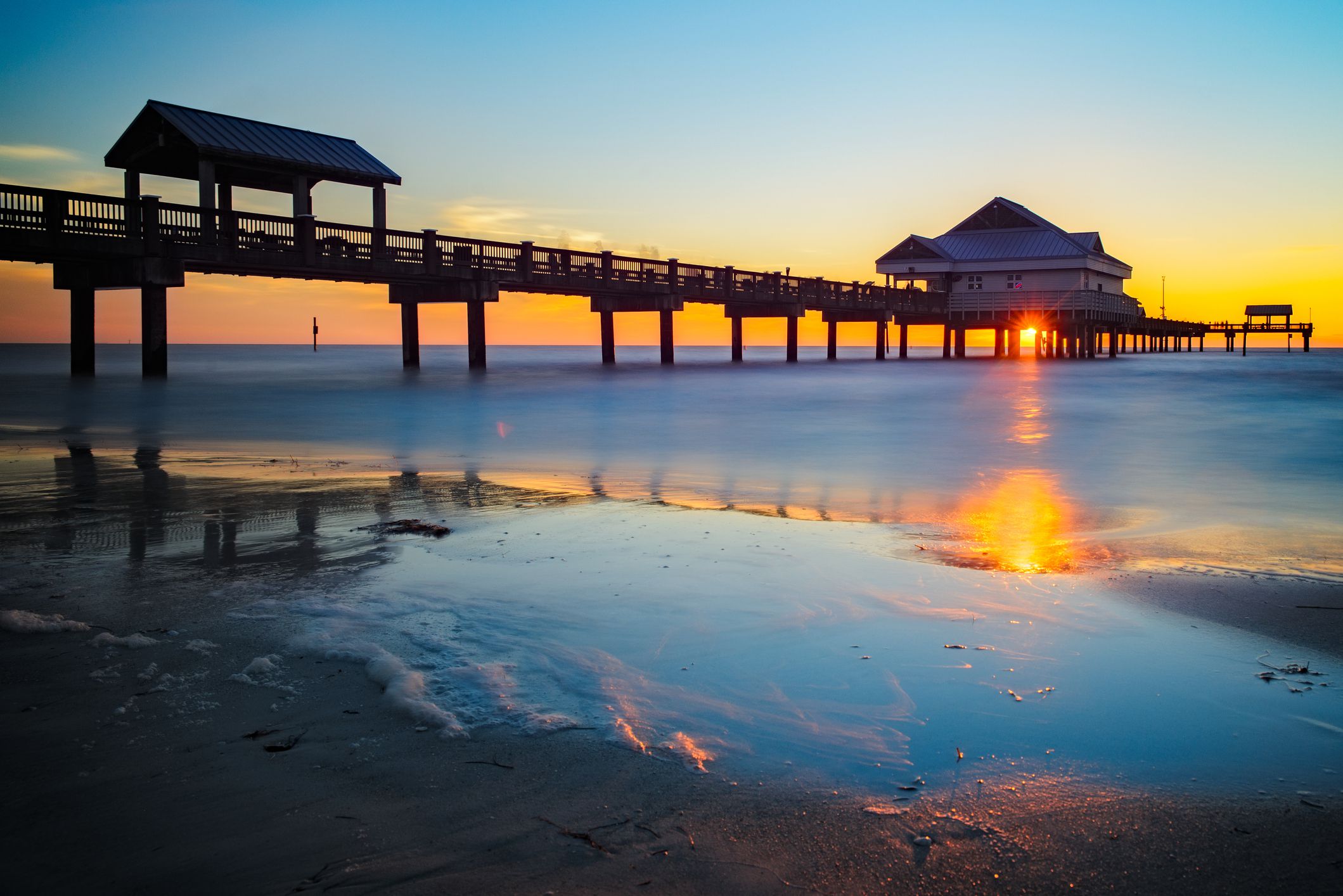 Sunset through Pier 60, Clearwater Beach, Clearwater, Florida with beach and ocean on sand in the foreground