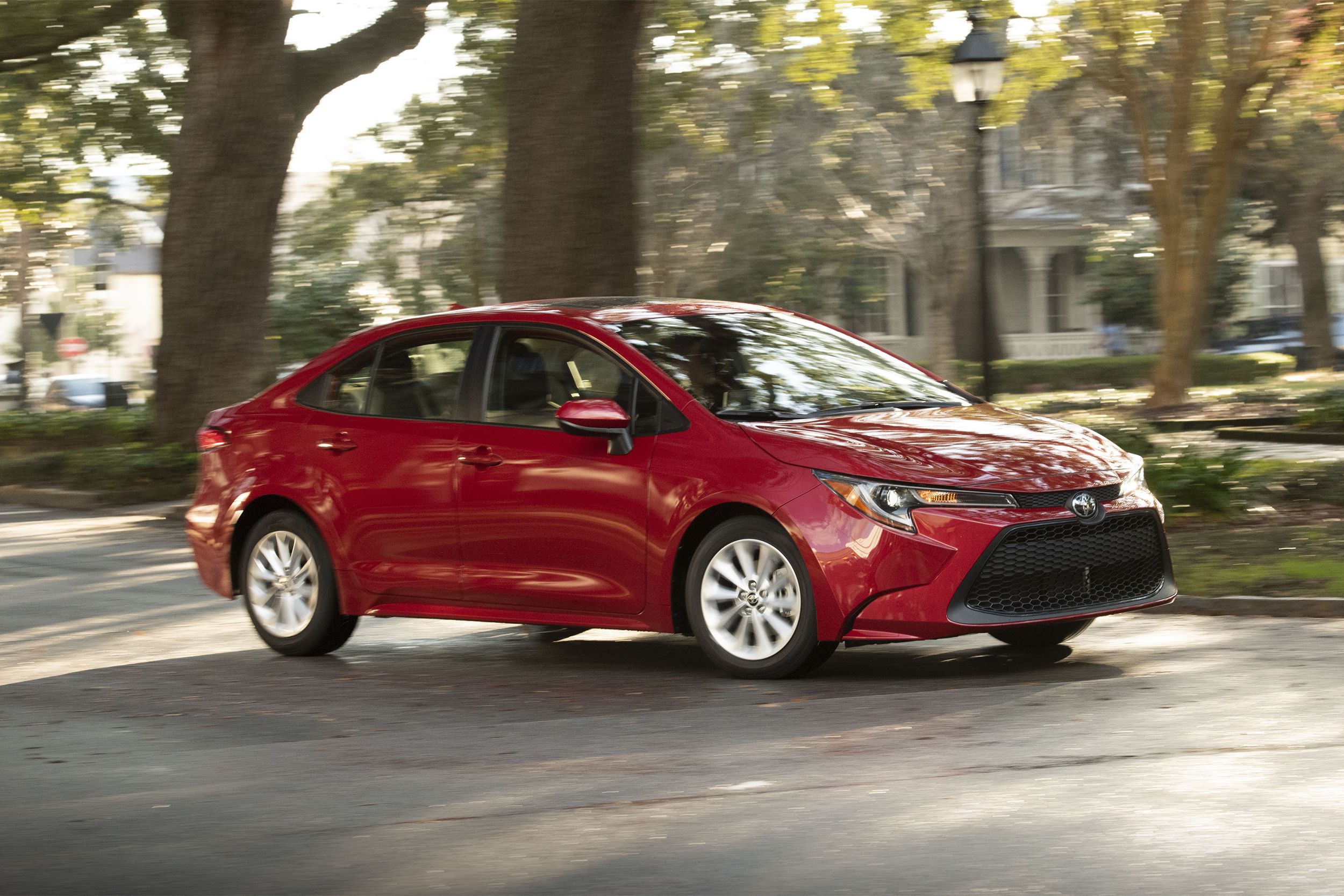 Red Toyota Corolla driving on suburban street