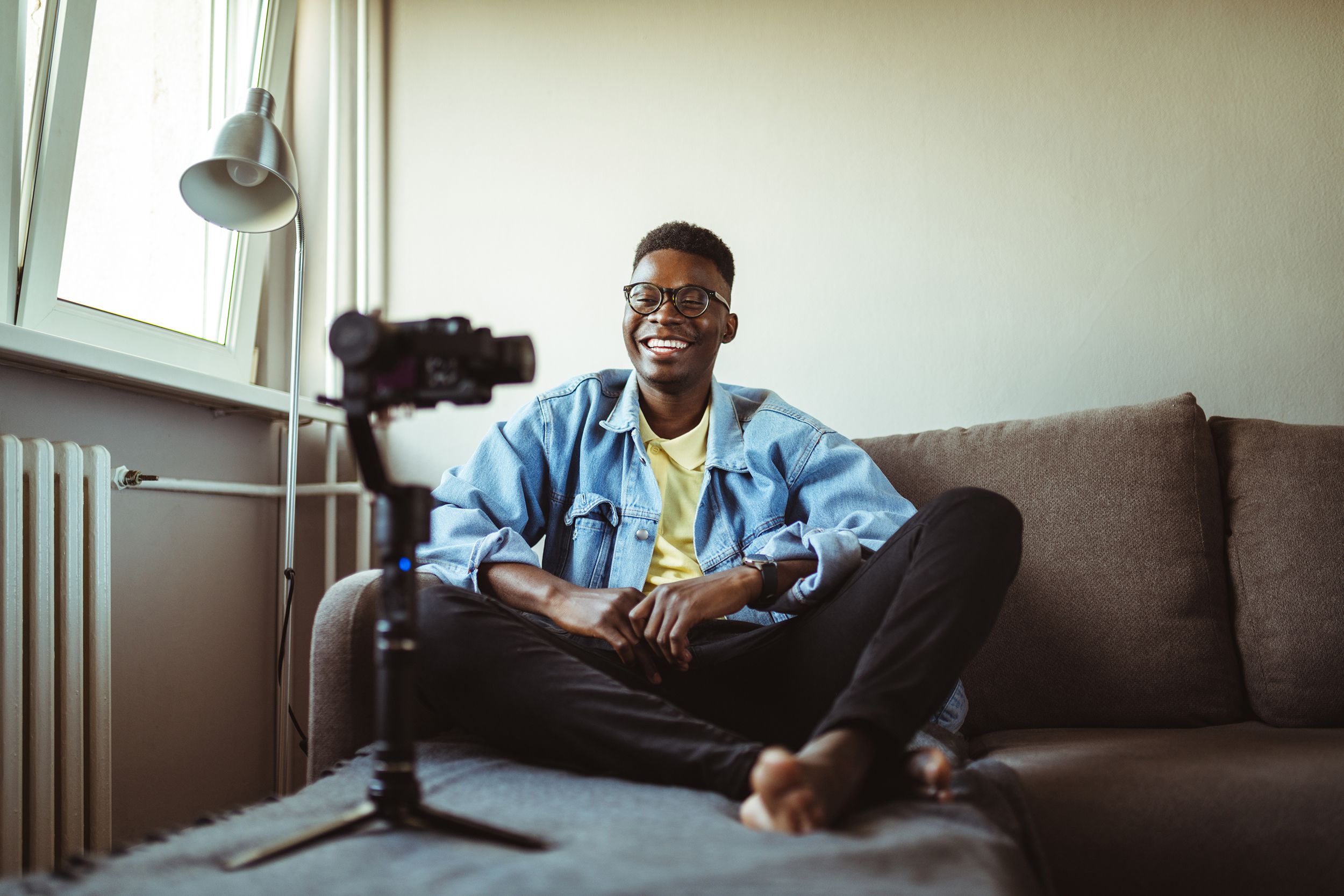 Young male content creator making video while sitting at home on sofa
