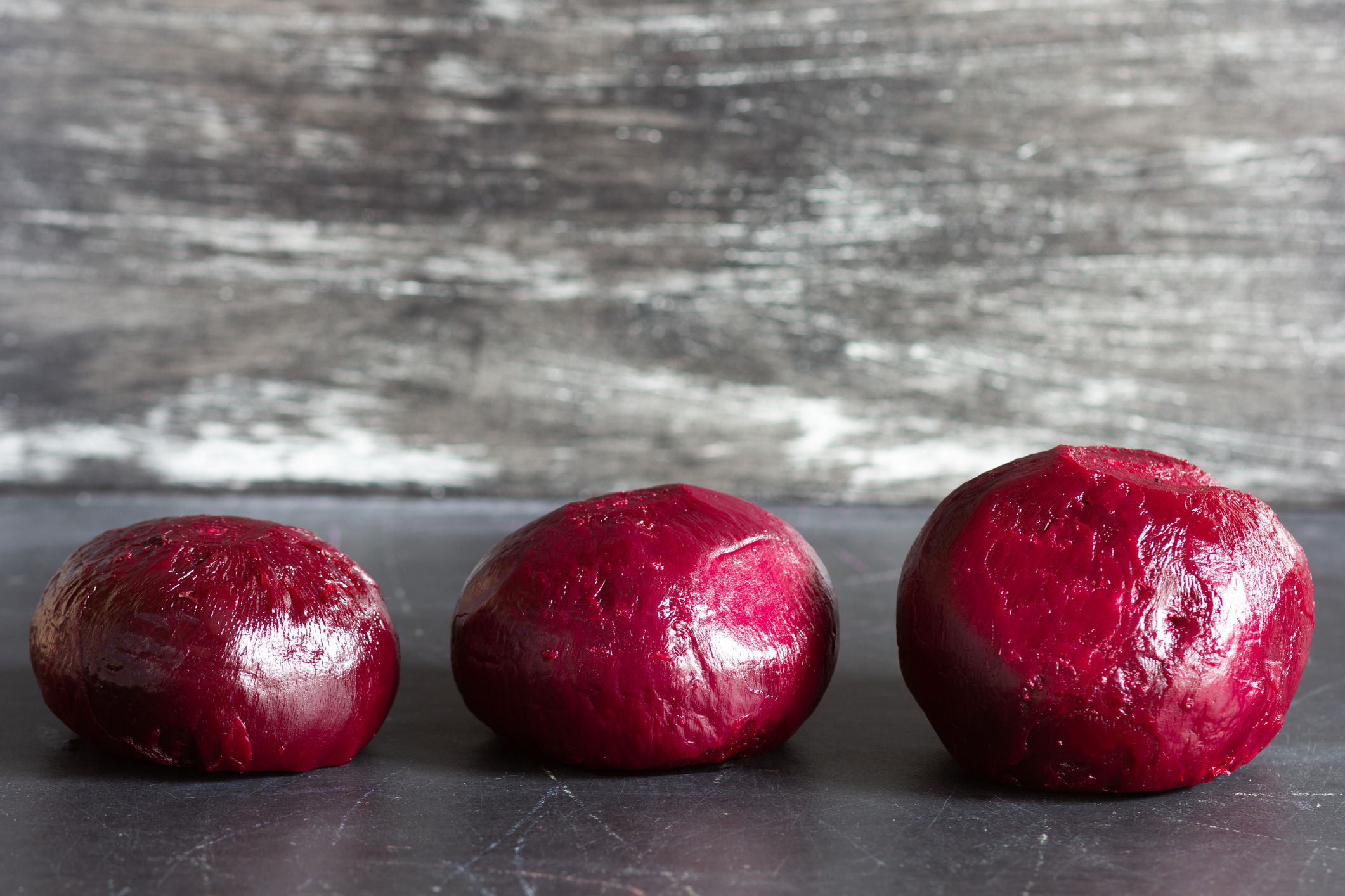 three roots of cooked peeled beet in a row on black background