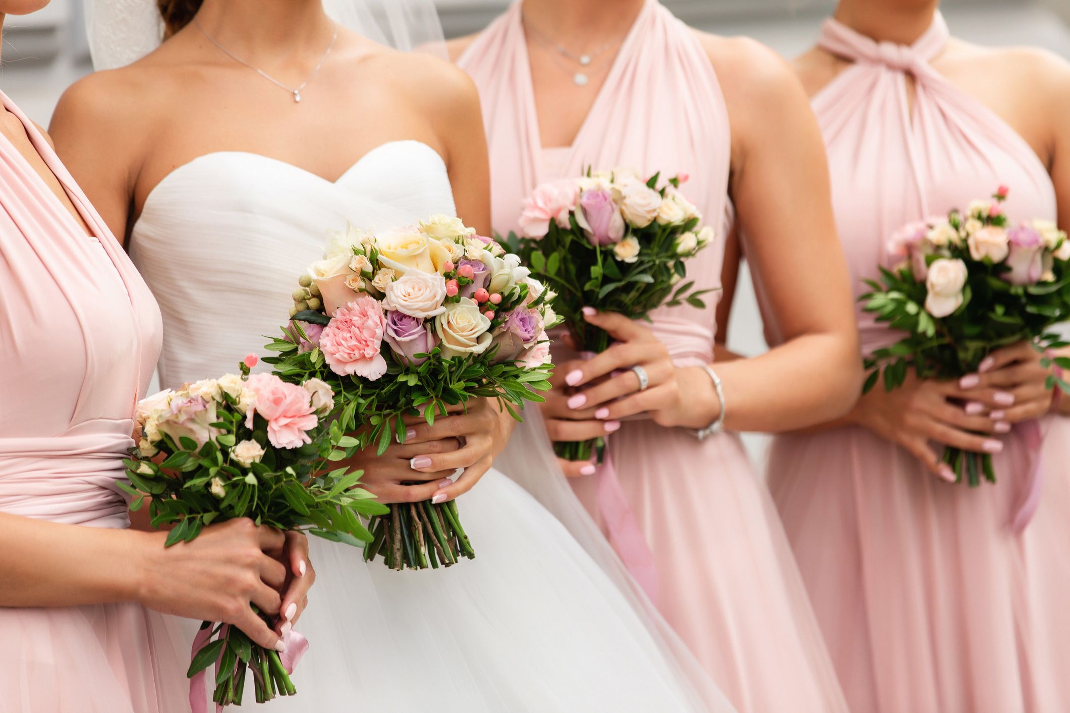 Bride and bridesmaids in pink dresses posing with bouquets at wedding day. Happy marriage and wedding party concept