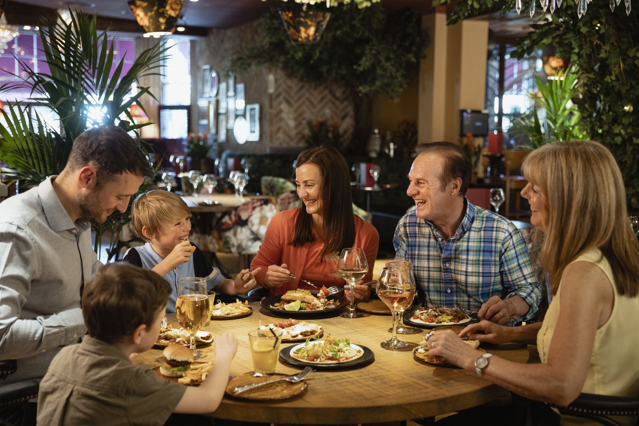 A family having a meal at a restaurant. They are laughing with each other.