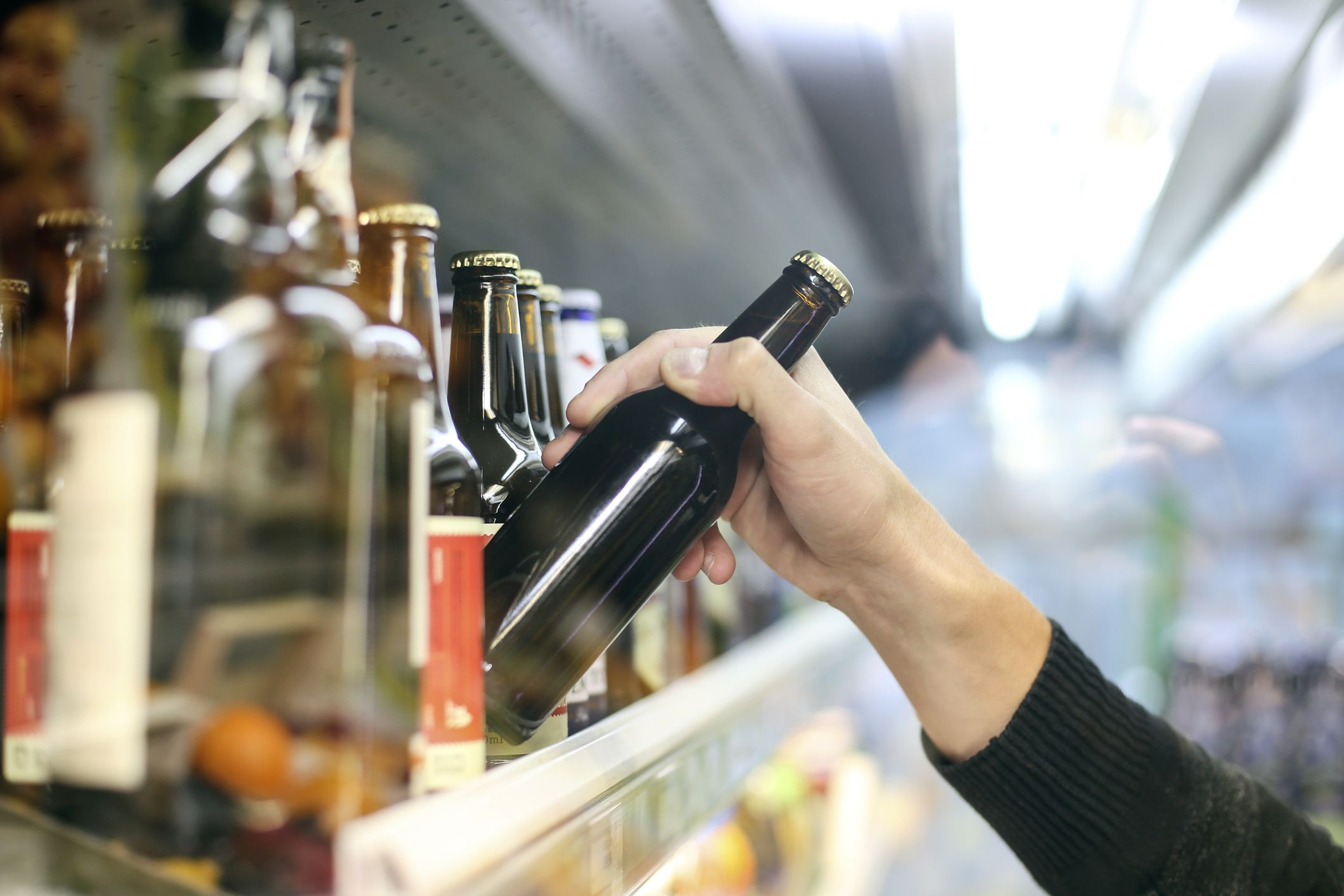 Unrecognizable man buying beer in a supermarket store.