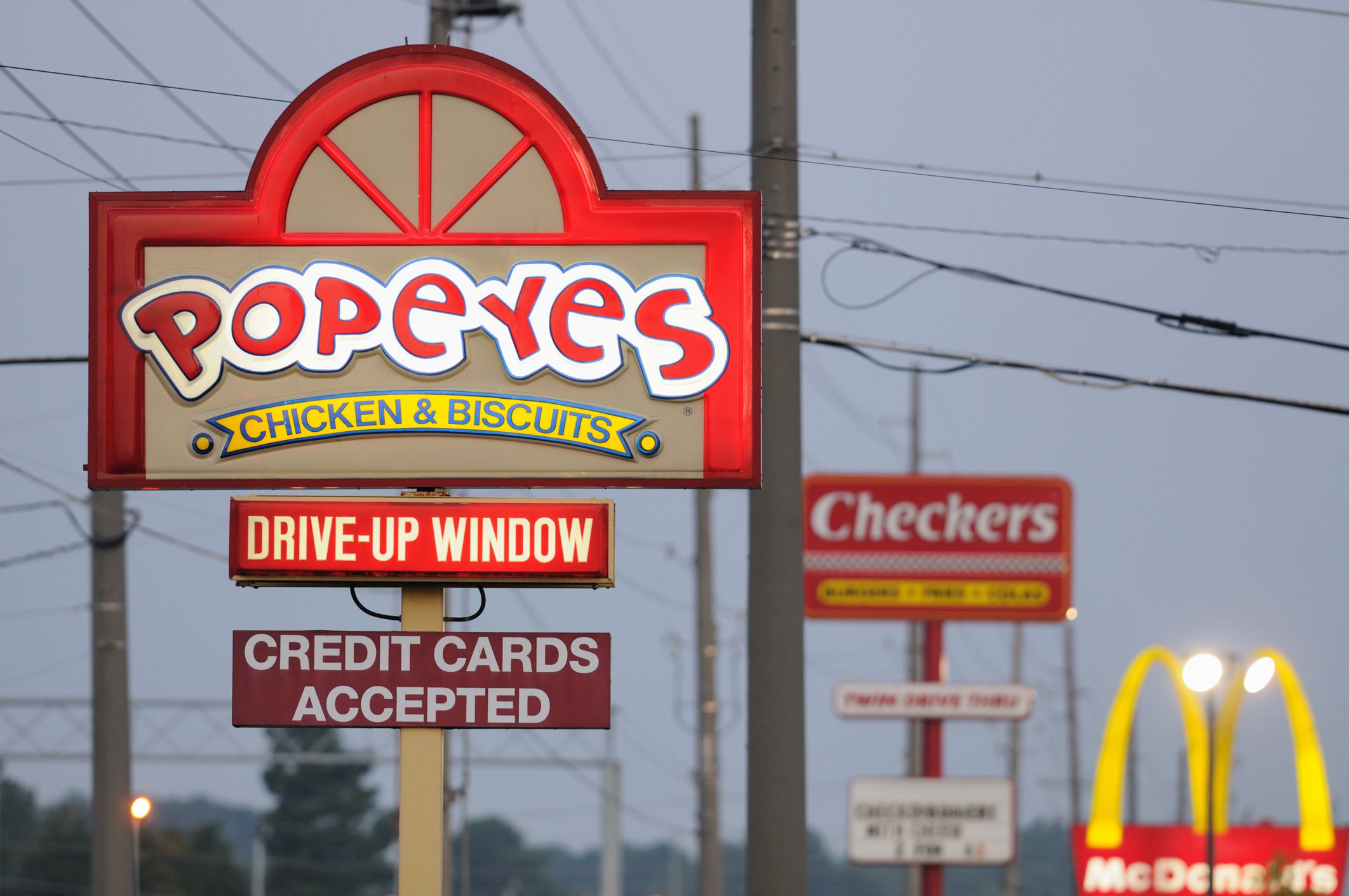 Huntsville, Alabama, USA - August 3, 2011: Illuminated fast food signs at sunrise. Popeyes, Checkers, and McDonalds signs on University Drive in Huntsville, Alabama, just west of Jordan Lane.