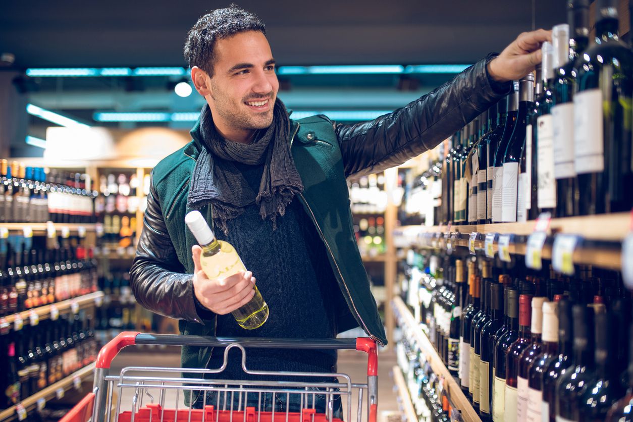 Young man in a supermarket choosing wine