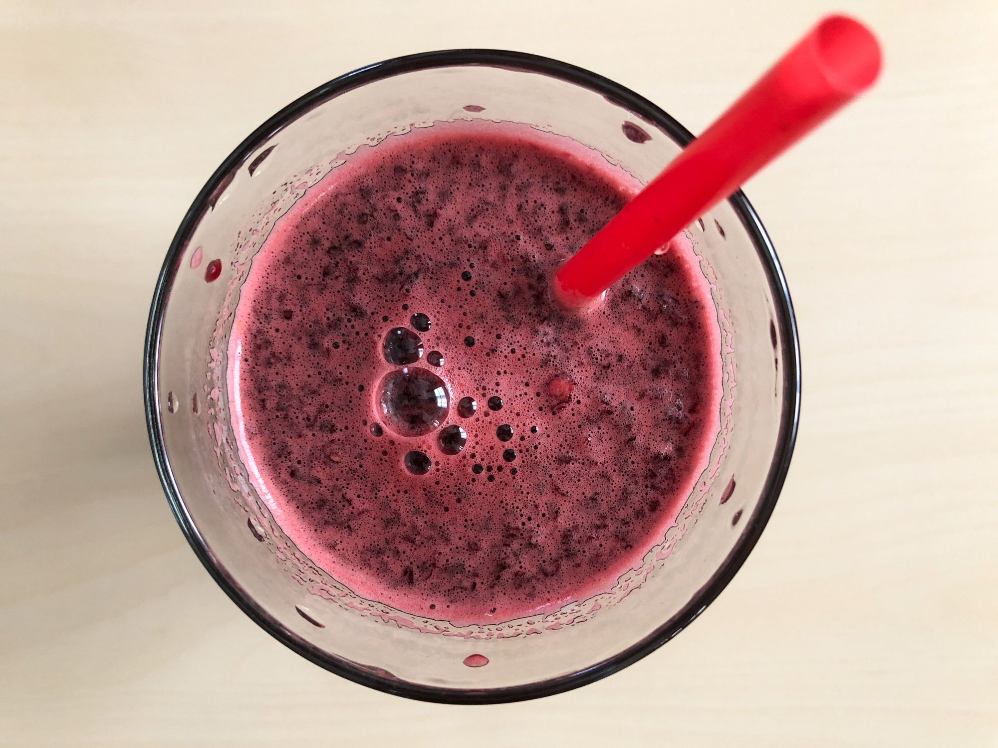 Close up of glass of healthy fresh squeezed carrot and beet juice from above on neutral table background