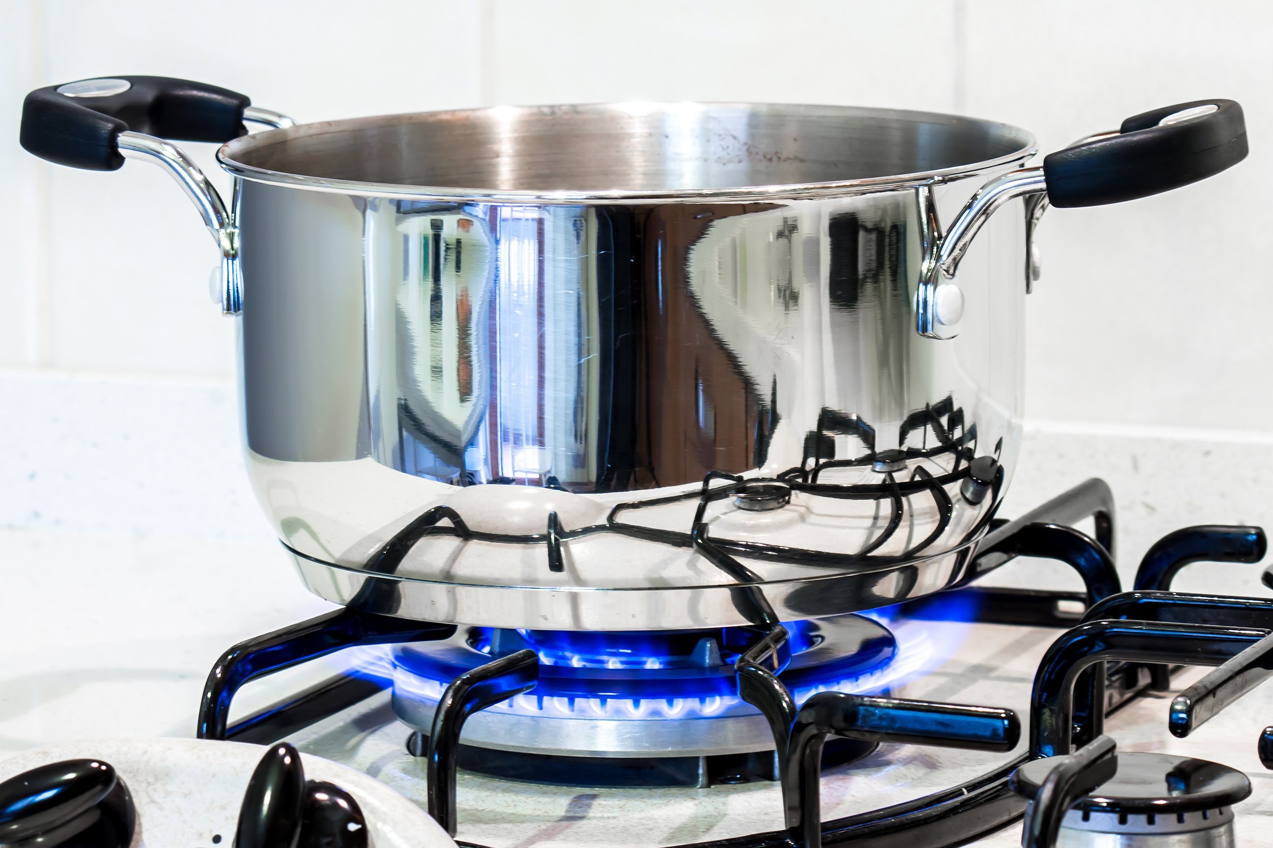 cook with a steel pot on the stove in the kitchen