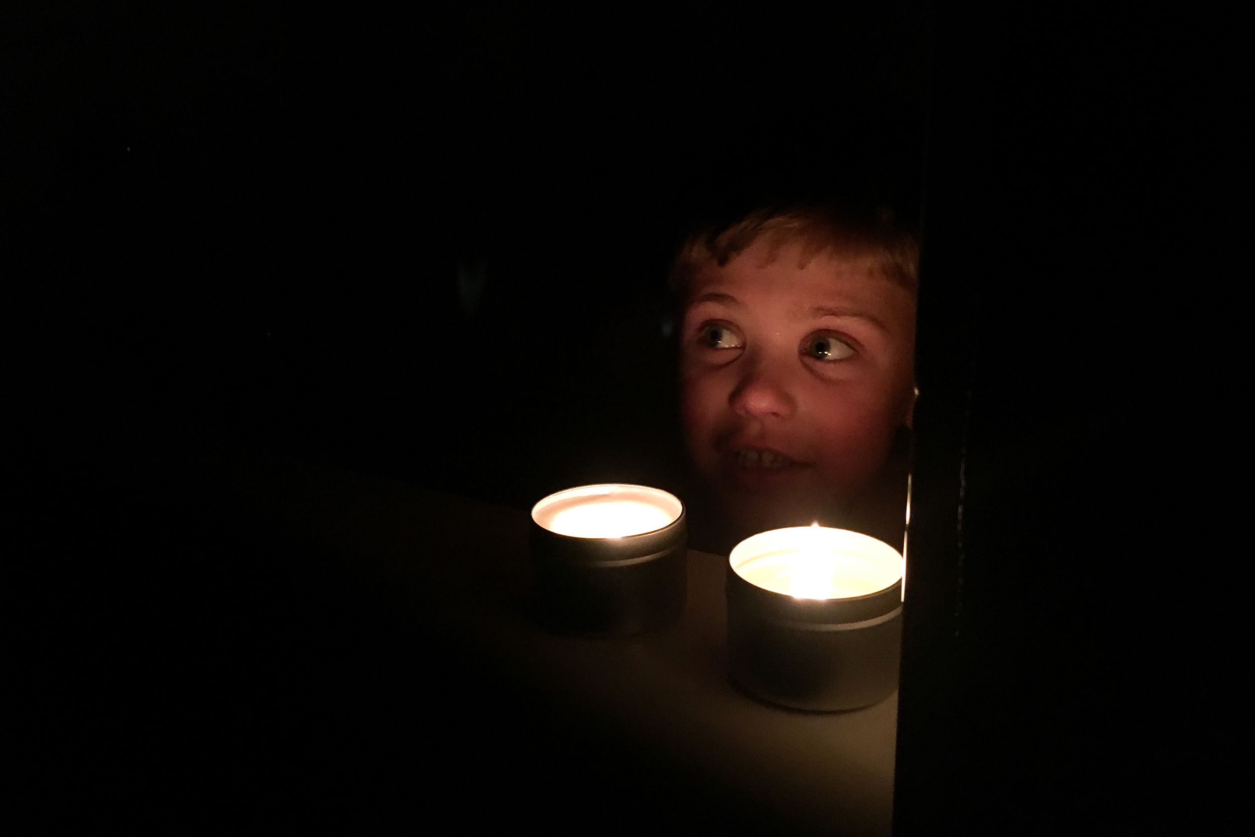 child taking a bath with two candles burning