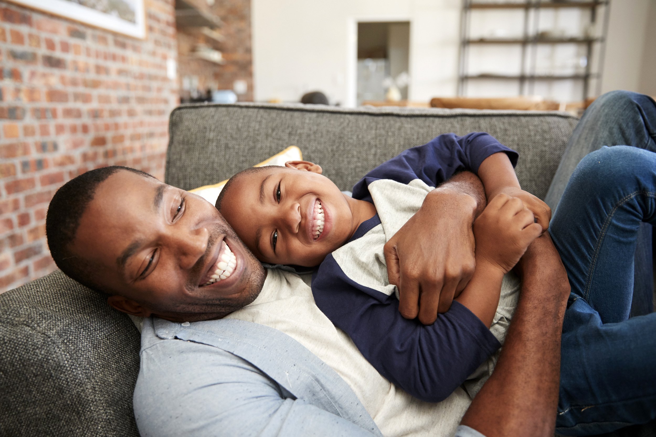Father and son laughing on the couch