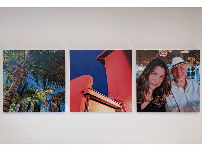 Three square photos mounted on a white wall: palm tree with blue sky, a close-up of a red structure against the sky, and a smiling man and woman sitting together indoors.