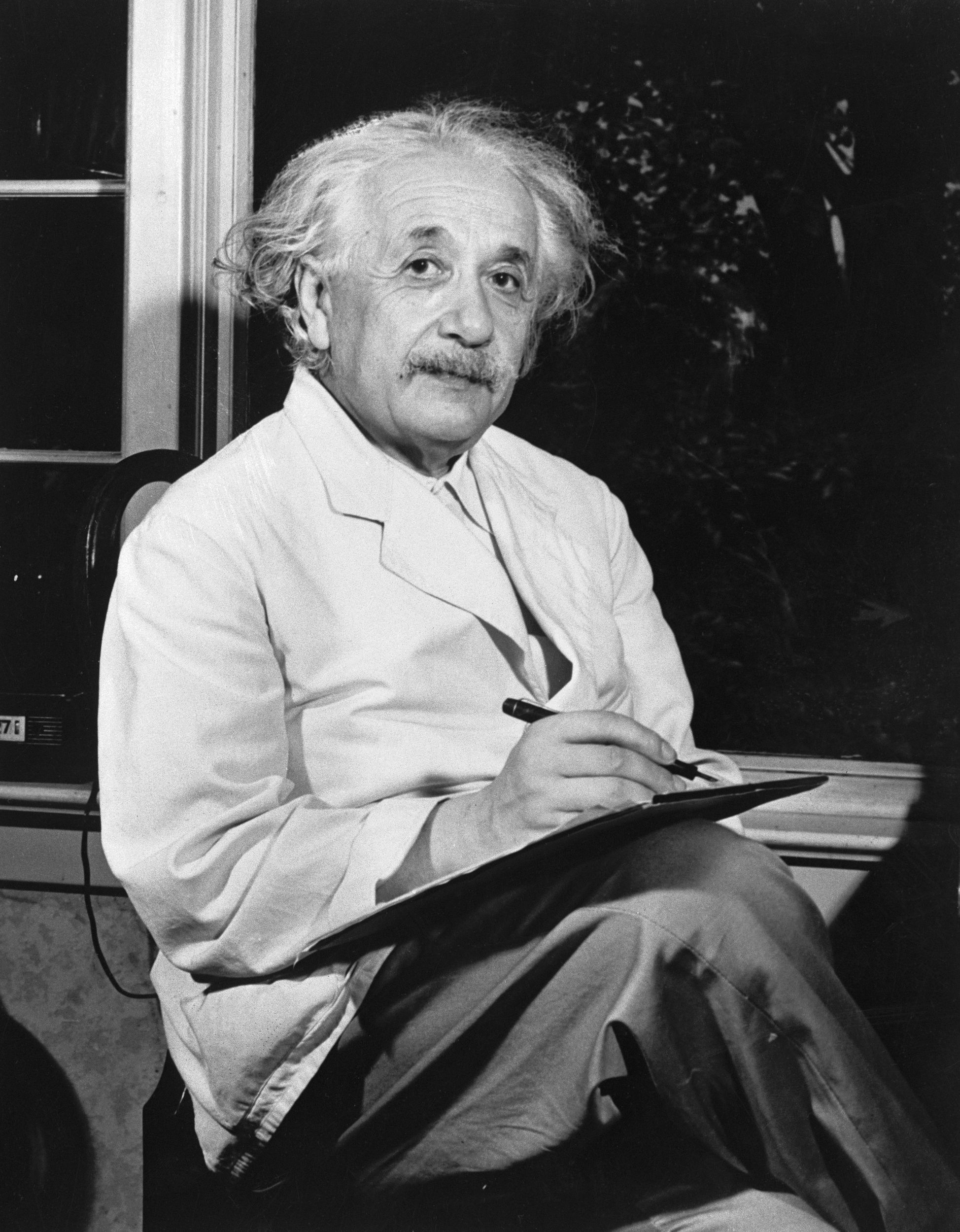 Albert Einstein is seated inside by the window, looking towards the camera, circa 1940s-50s, black and white