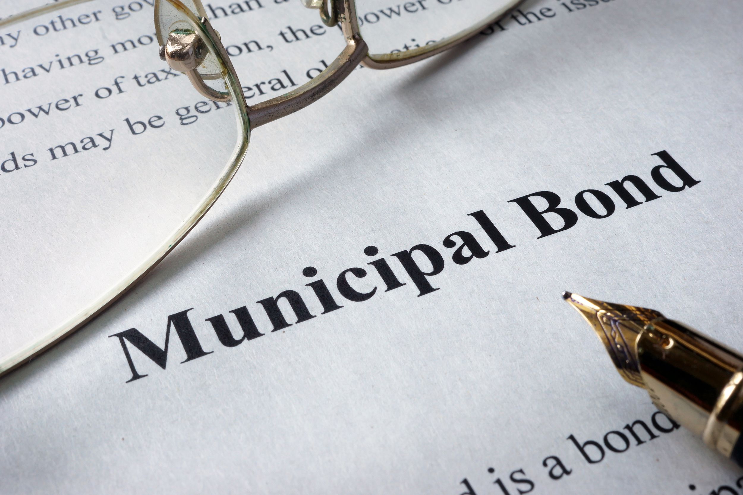 Closeup of 'Municipal Bond' on white paper with pen on the lower right and glasses on the upper left, text above and below it