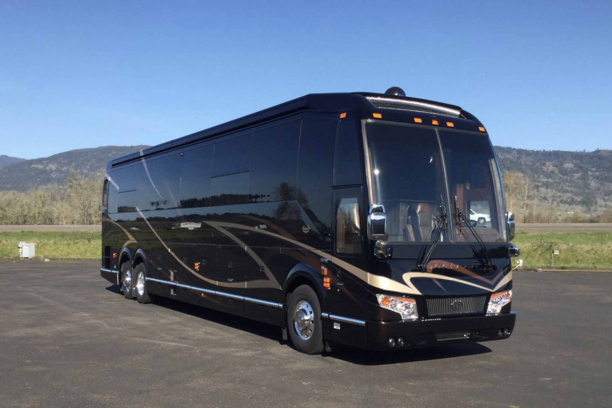 Exterior of Marathon Coach on a paved lot, mountains and a clear blue sky in the background